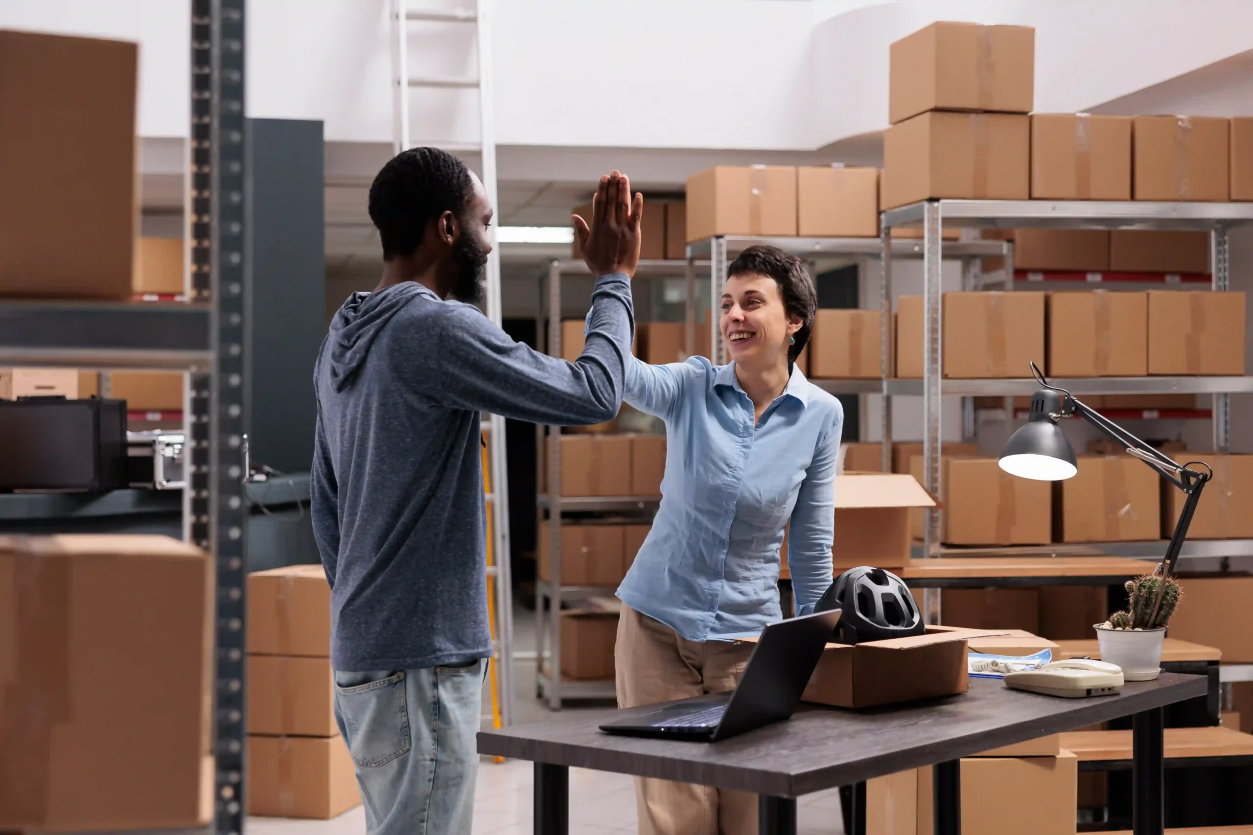 Warehouse employees celebrating successful order fulfillment with a high-five.