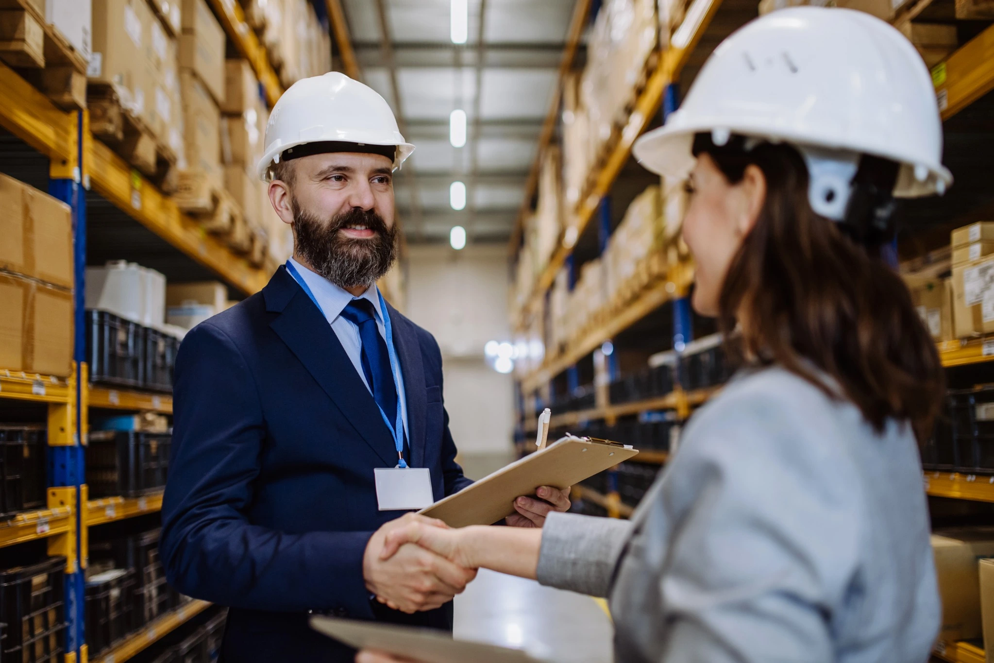 Business professionals shaking hands in a warehouse, representing a successful partnership in 3PL value-added services.