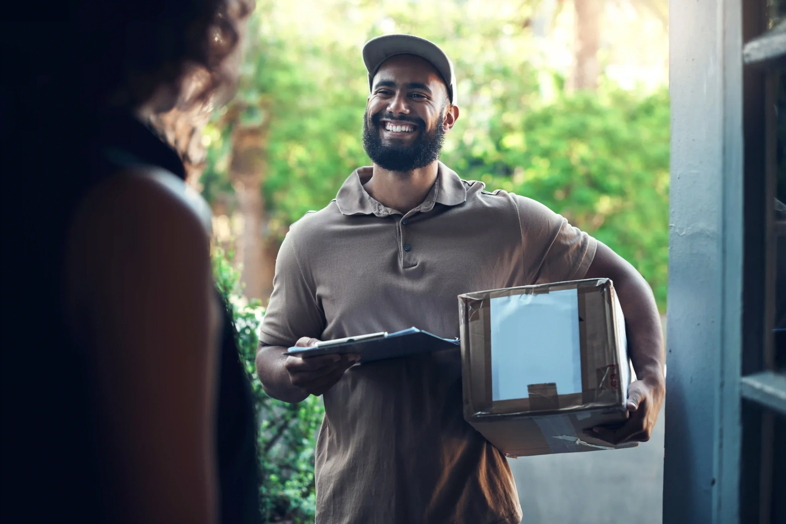 friendly last-mile delivery worker handing over a package to a recipient at their doorstep.