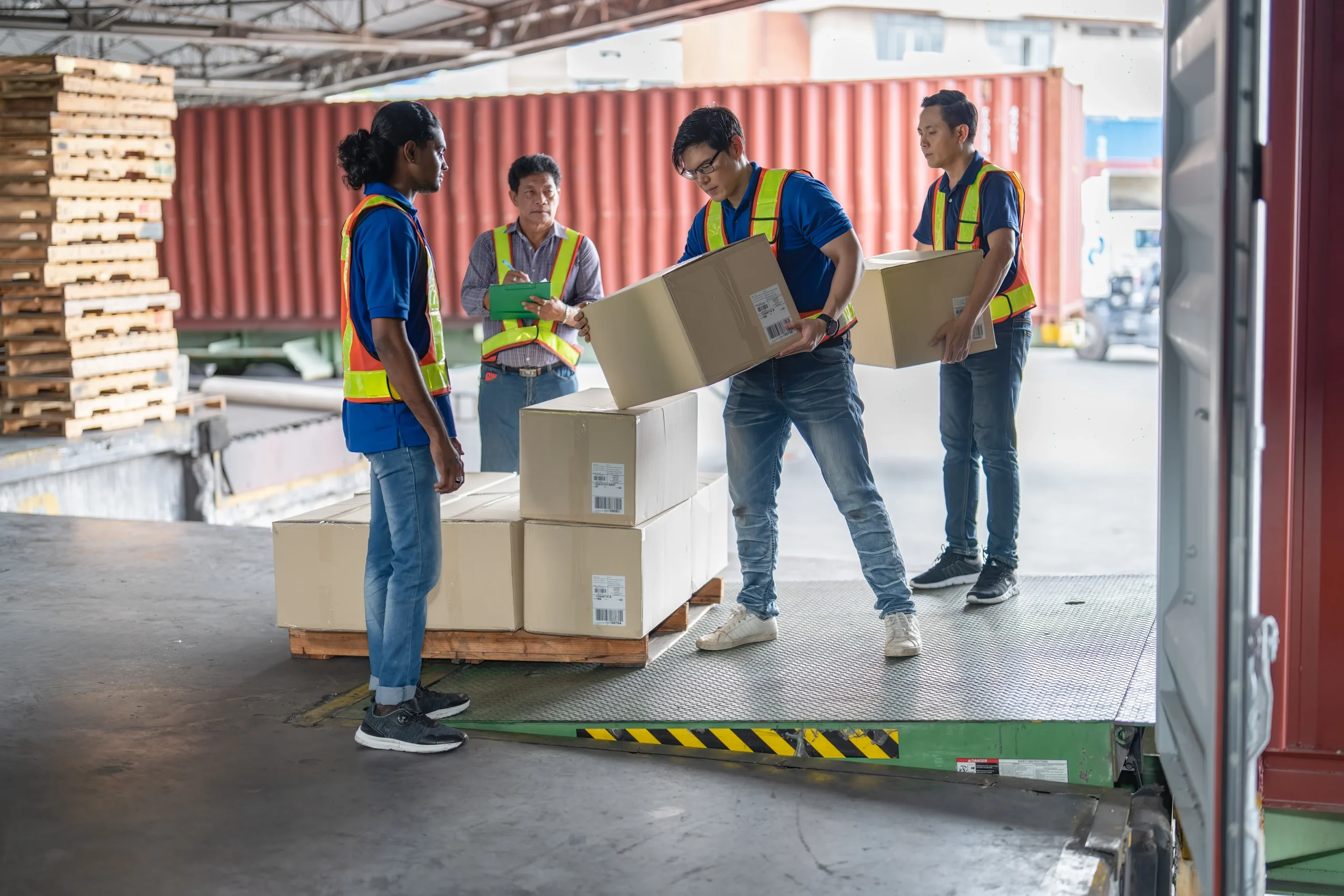 Logistics team transferring packages between trucks in a cross-docking facility, demonstrating the need for precise scheduling and coordination.