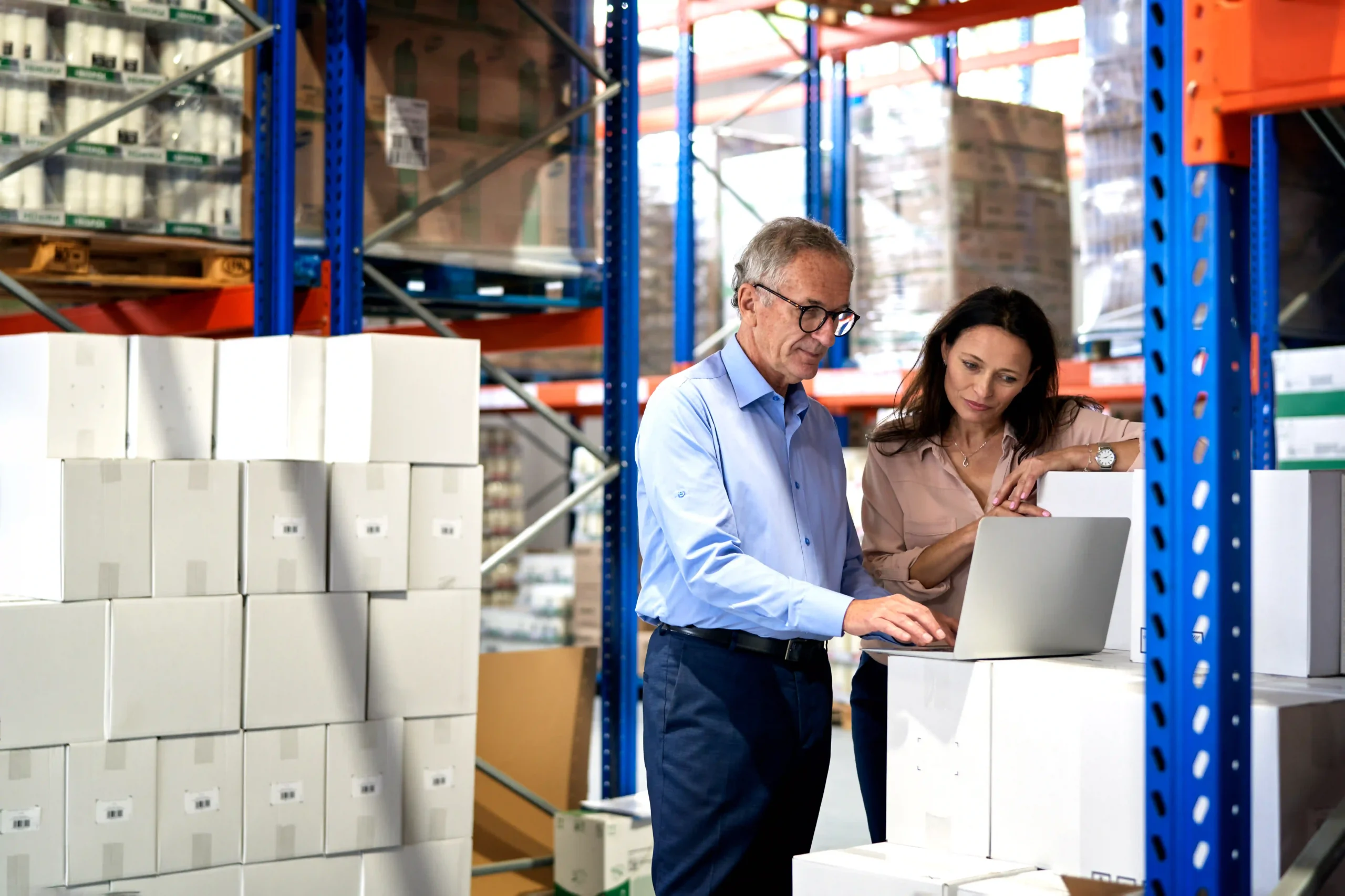 Mature logistics professionals discussing cross docking software in a warehouse setting to optimize supply chain operations.