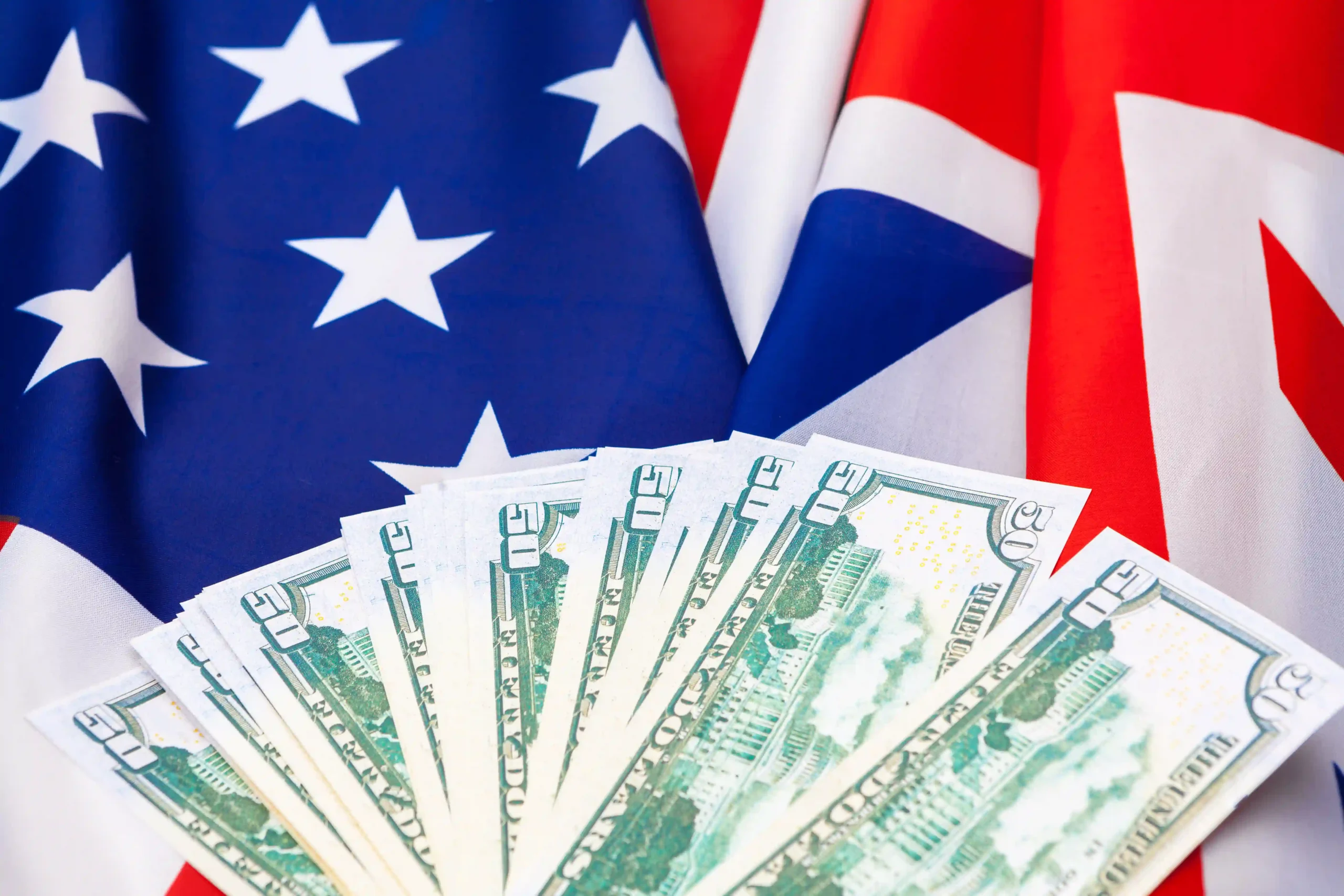 U.S. dollars in front of American and British flags, symbolizing financial markets' response to Trump tariffs and economic nationalism.