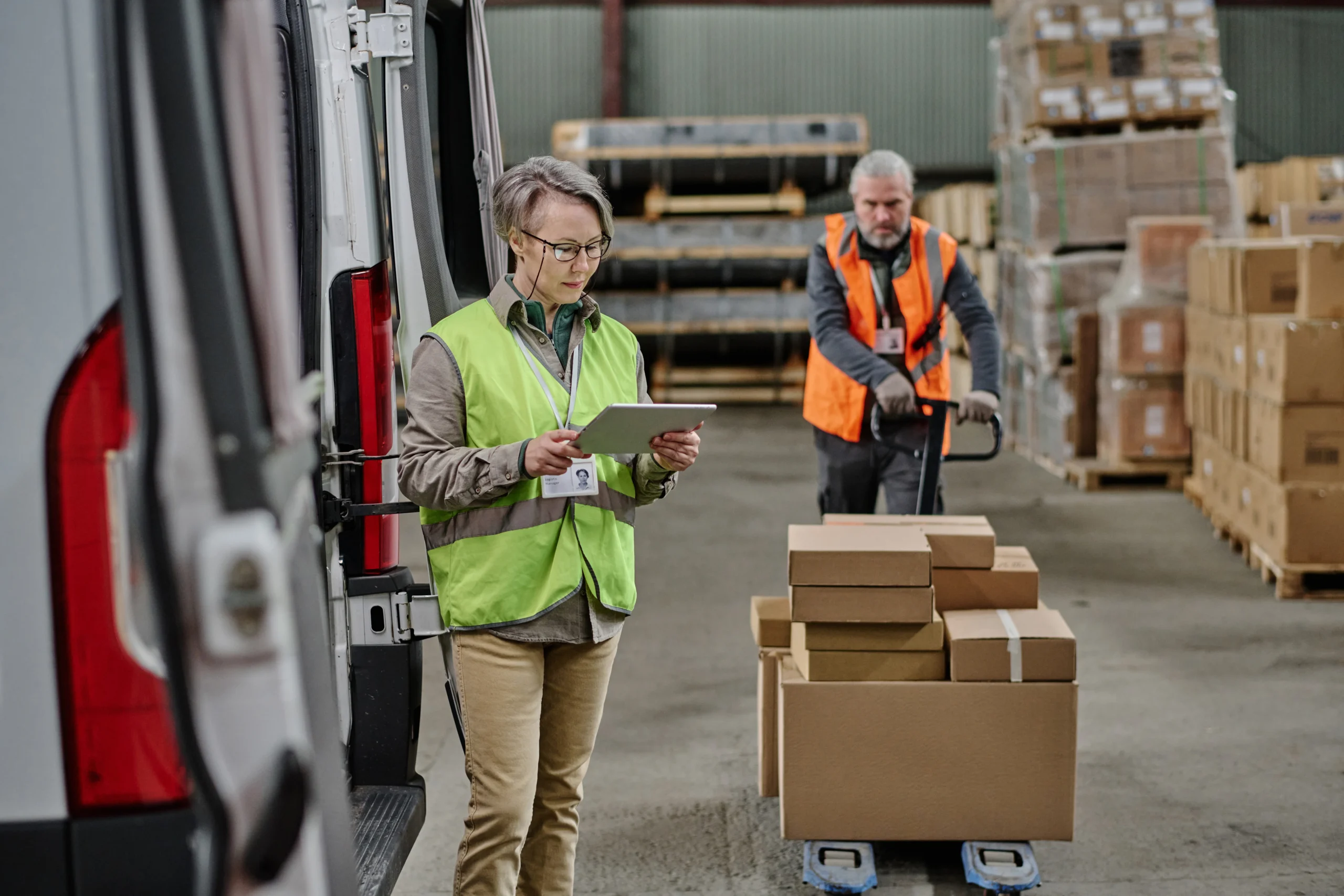 Warehouse foreman using a tablet to coordinate cross-docking operations during truck loading.