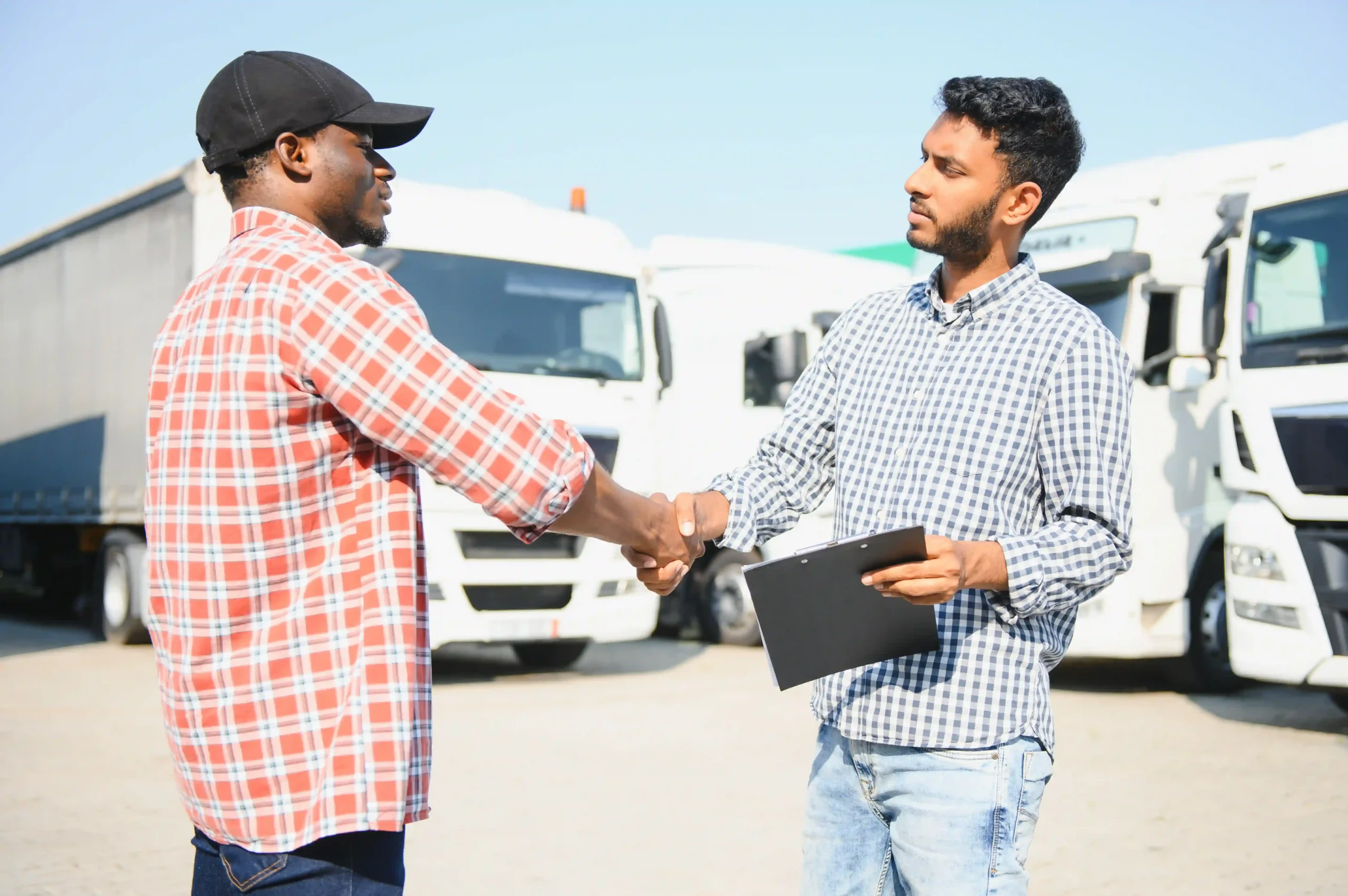 A logistics manager and truck driver discussing contract transport auto scheduling at a fleet yard.
