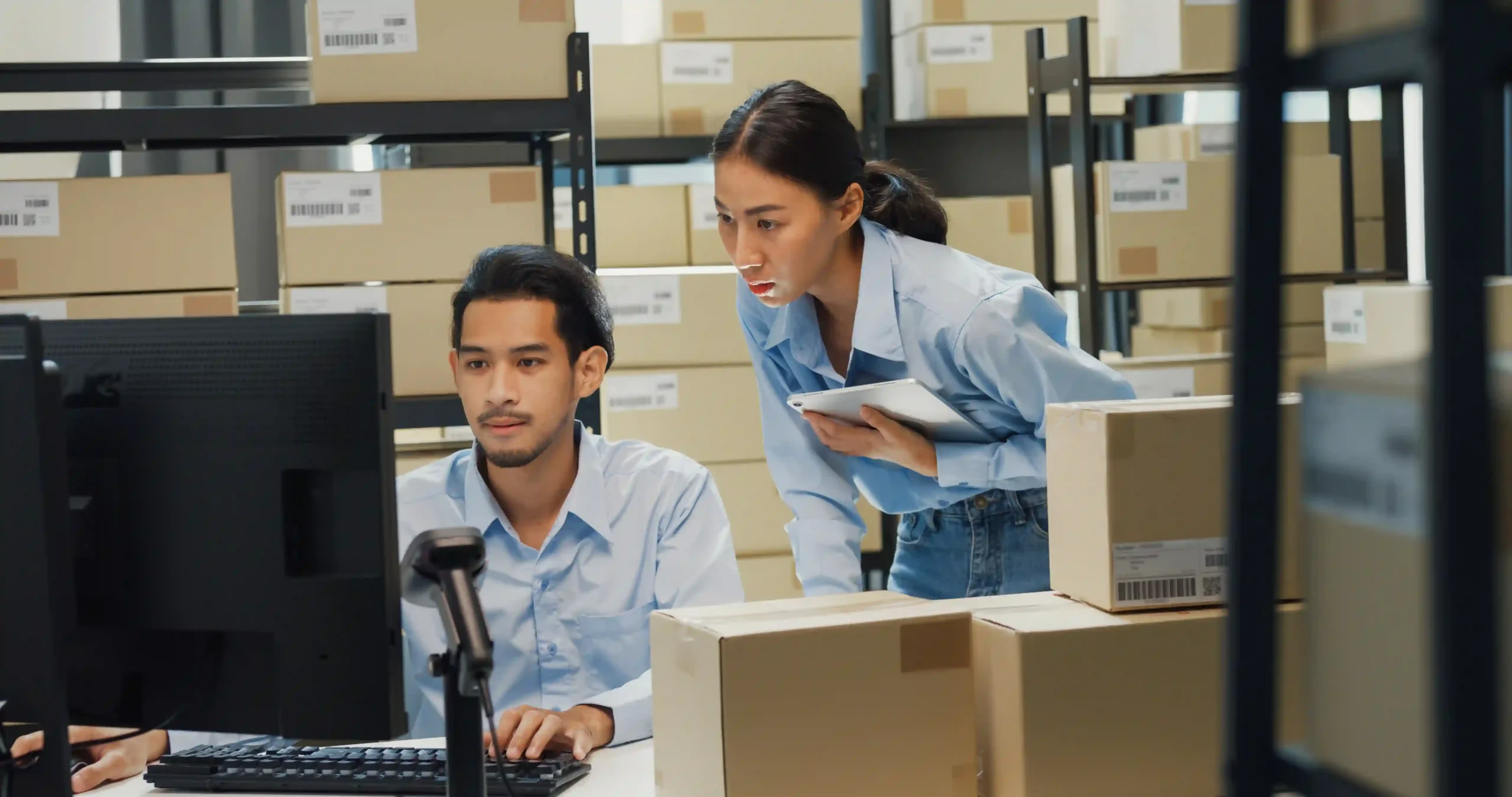 Warehouse staff using a barcode scanner to update an inventory management system report, improving accuracy in stock tracking.