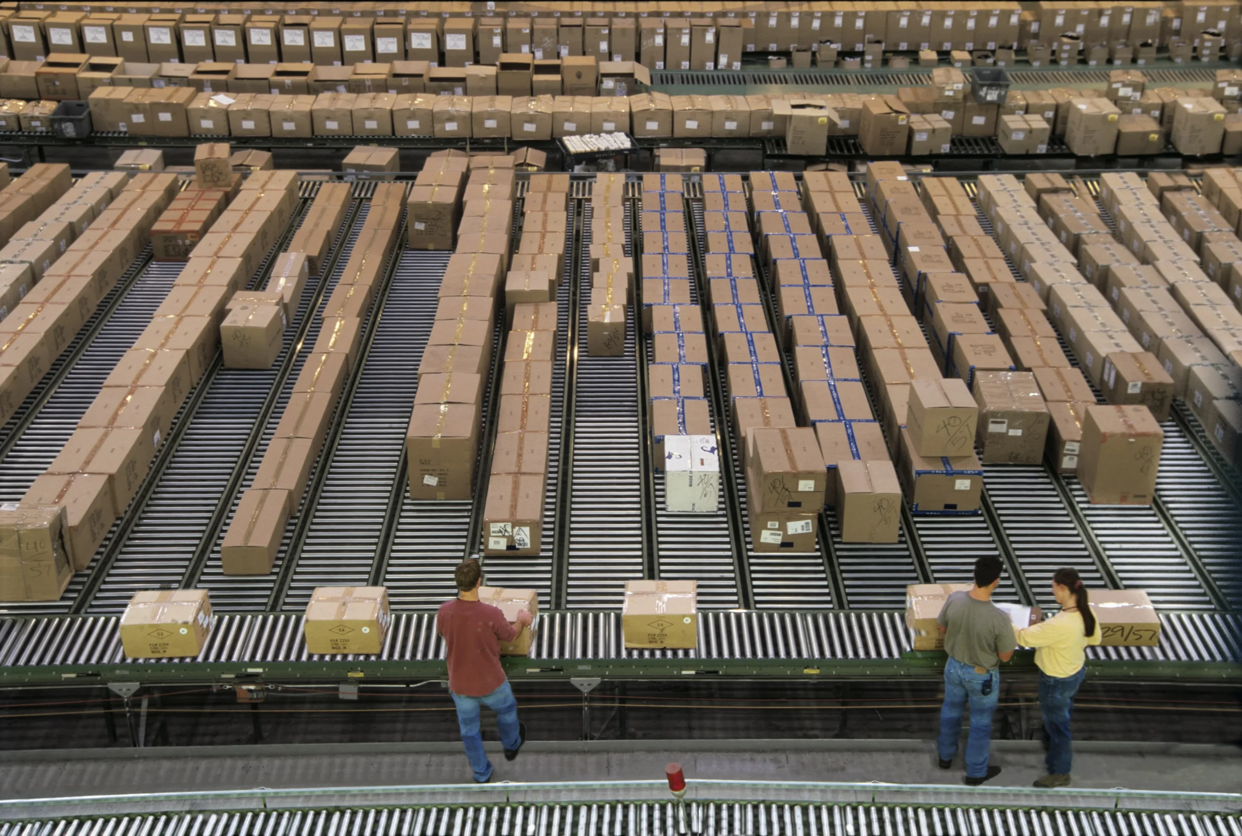 Industrial distribution warehouse with packages aligned on sorting conveyors as part of cross docking operations.