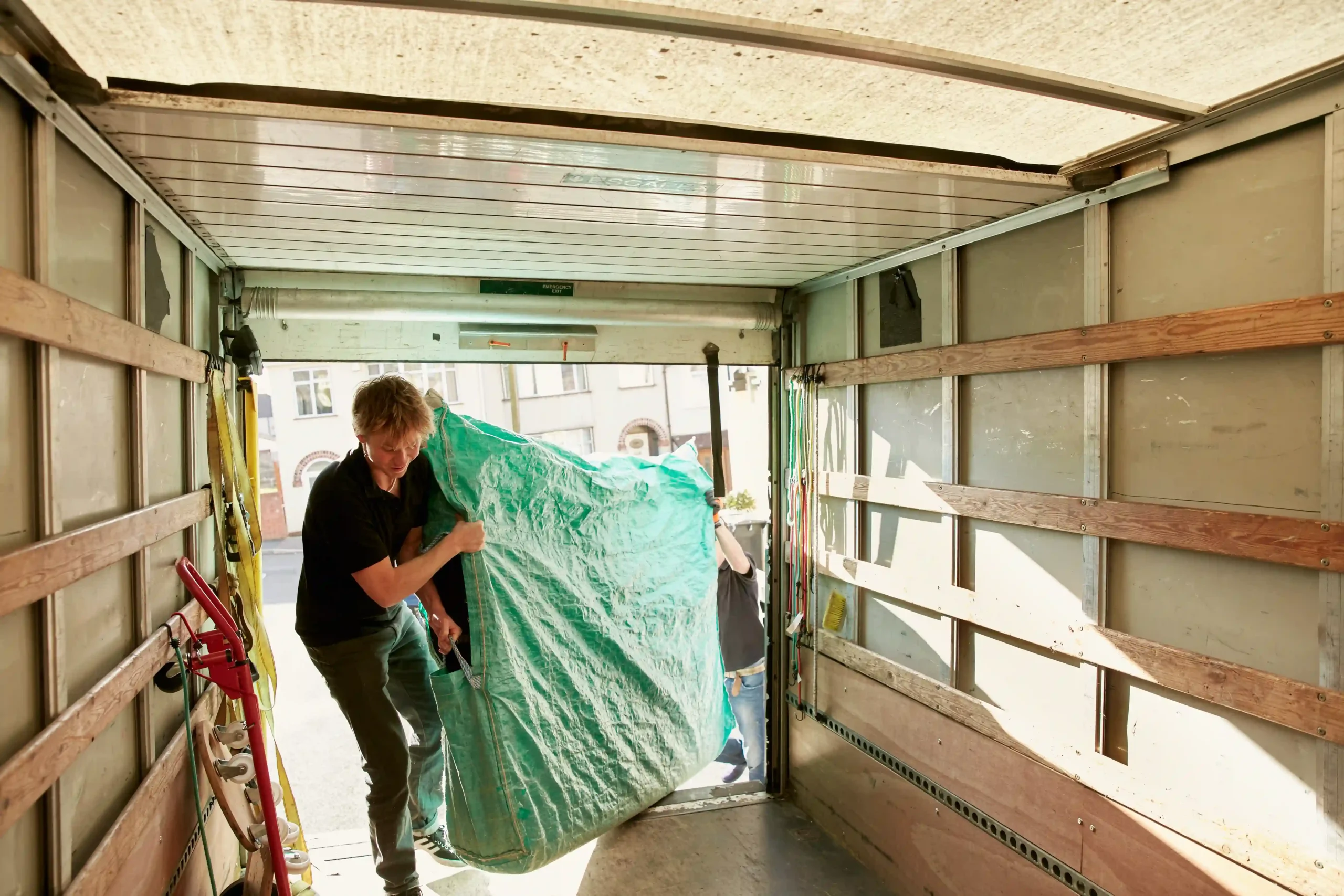 A moving professional securing furniture inside a truck as part of a contract furniture transport operation.