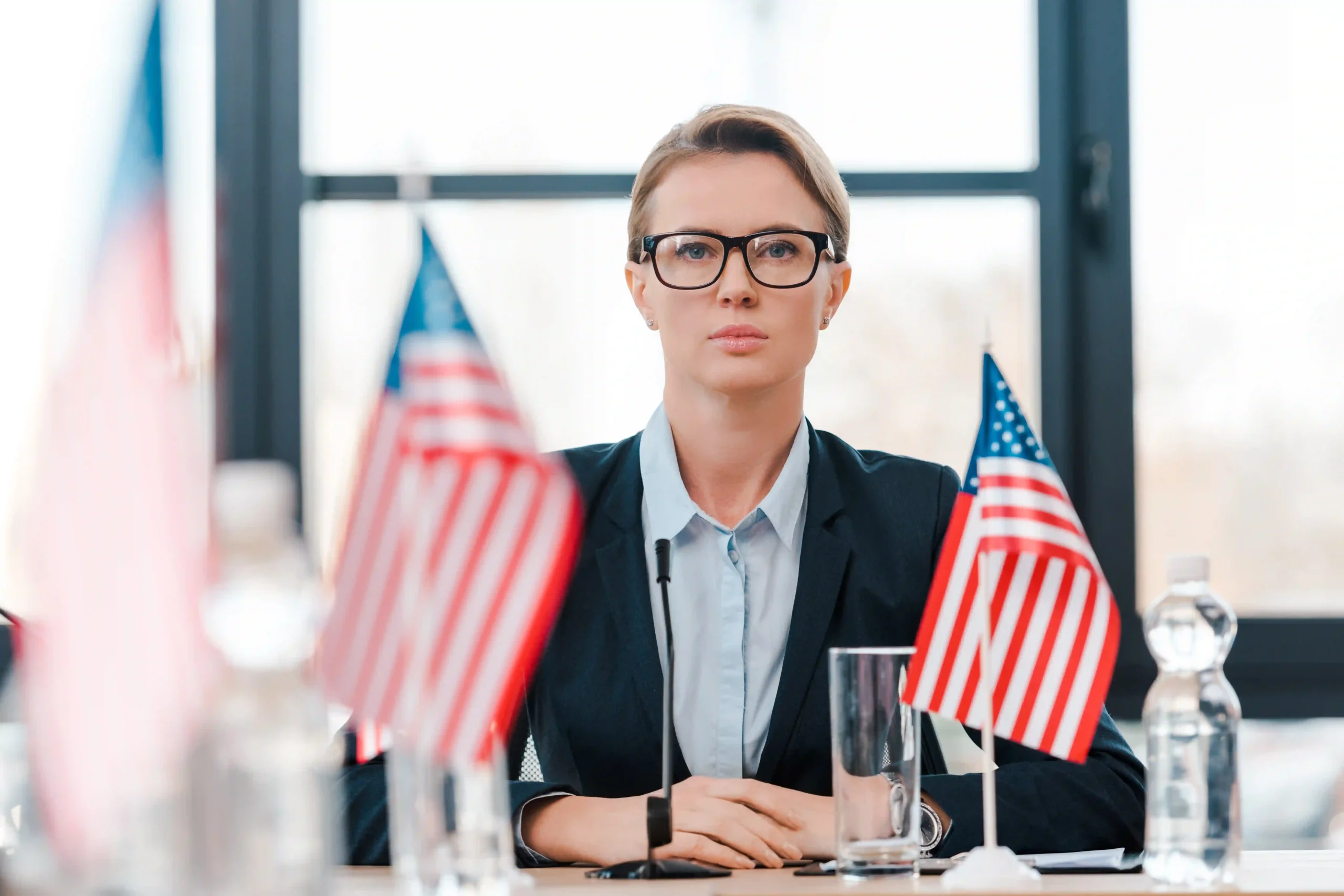 A diplomat in negotiations with American flags in the foreground, symbolizing U.S. trade policies under Trump tariffs.