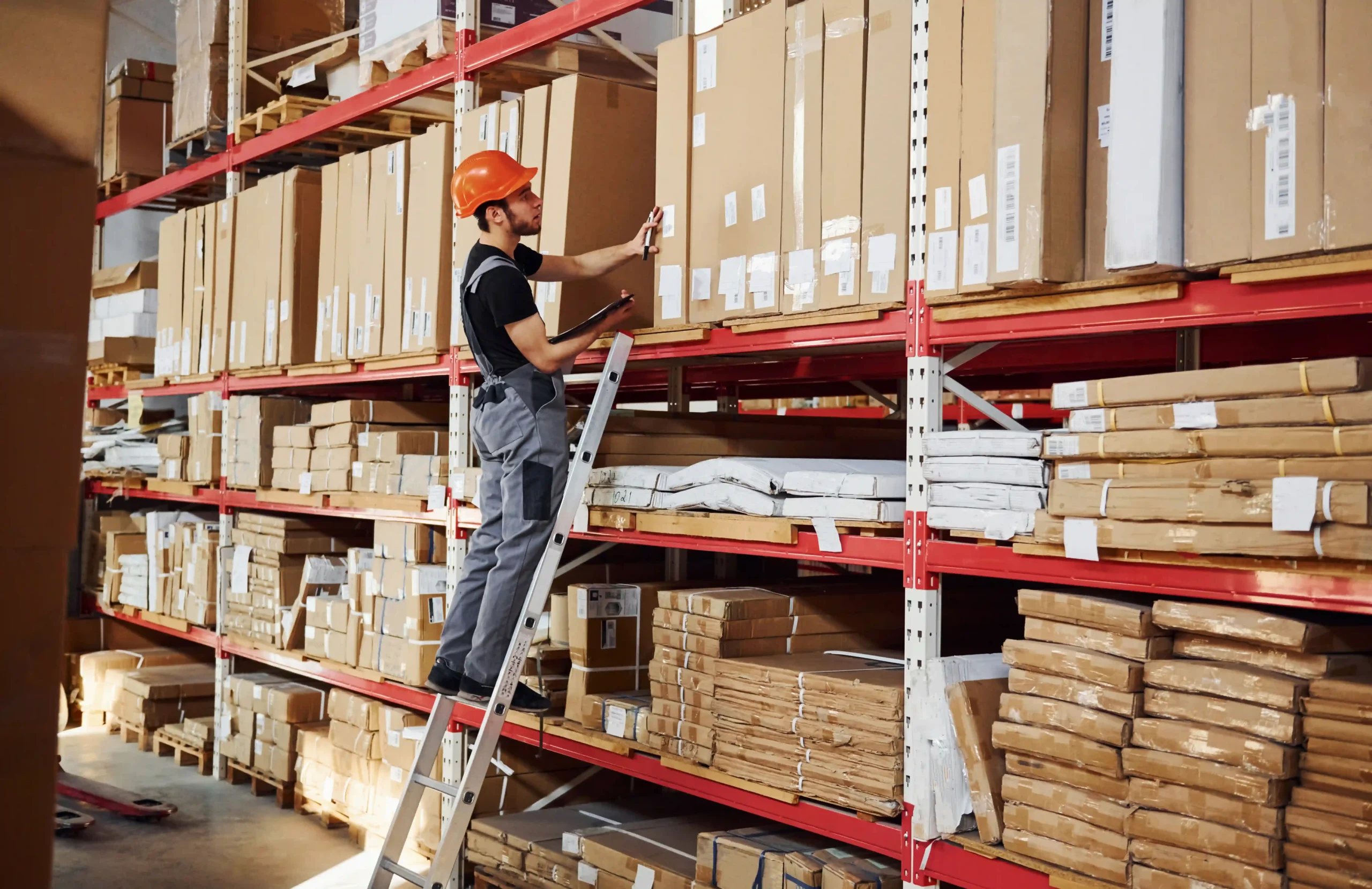 Warehouse worker accessing inventory using a ladder in a vertical storage system with labeled boxes.
