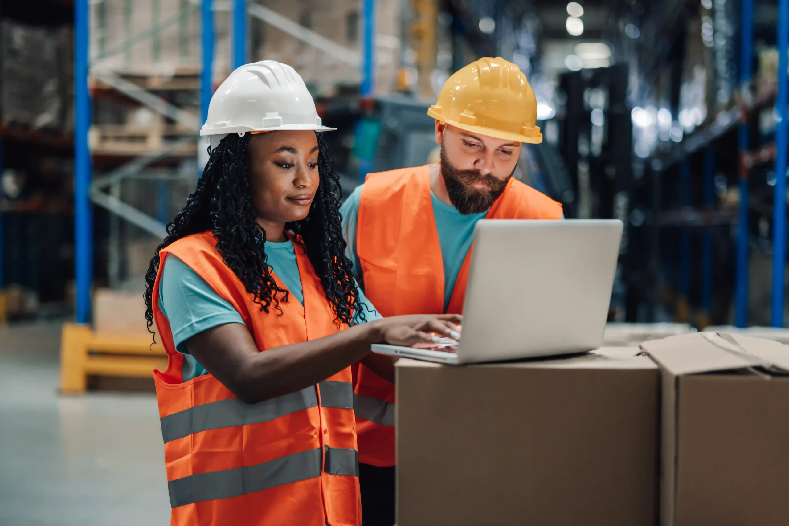Two warehouse workers using a laptop to check inventory, demonstrating technology in universal contract logistics.
