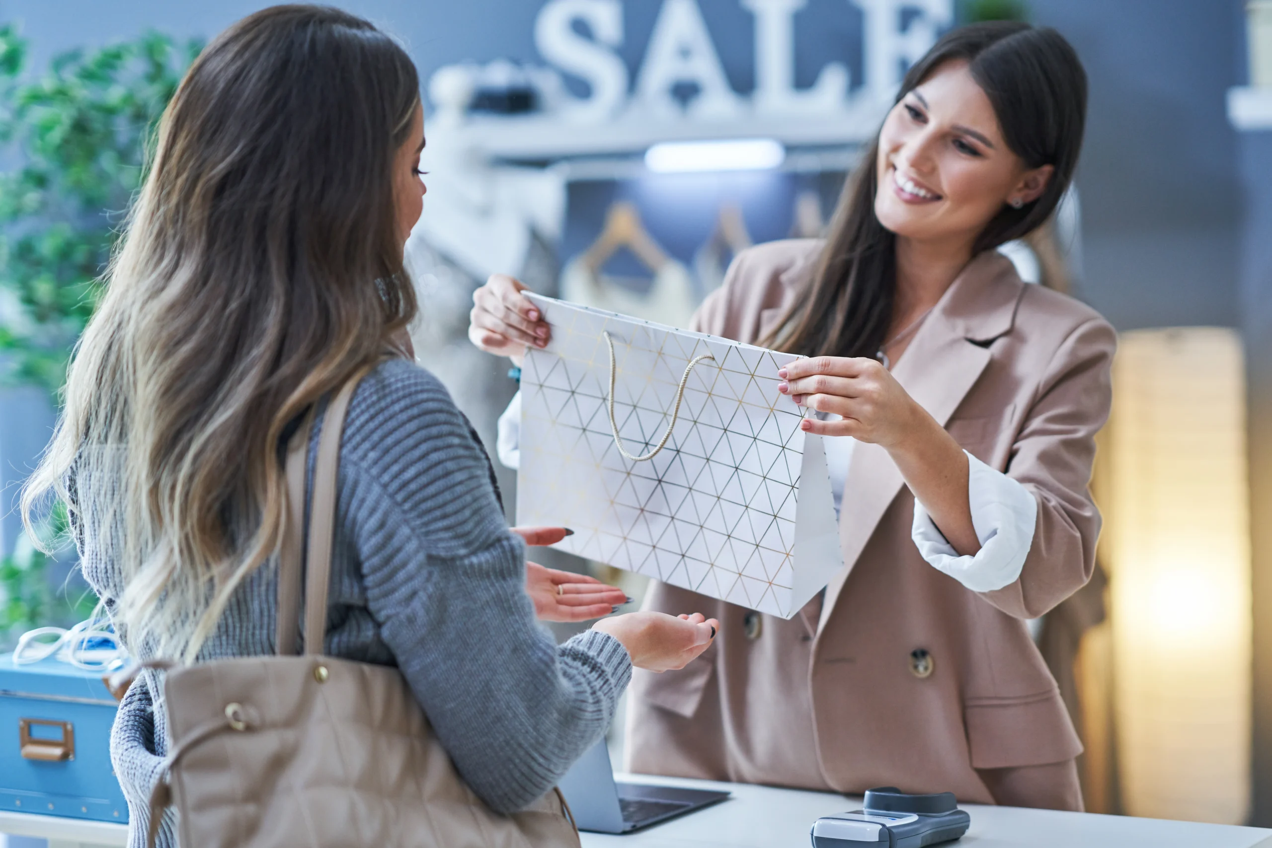 A retail employee handing a shopping bag to a customer in a clothing store, showcasing the importance of excellent Pick and Save customer service.