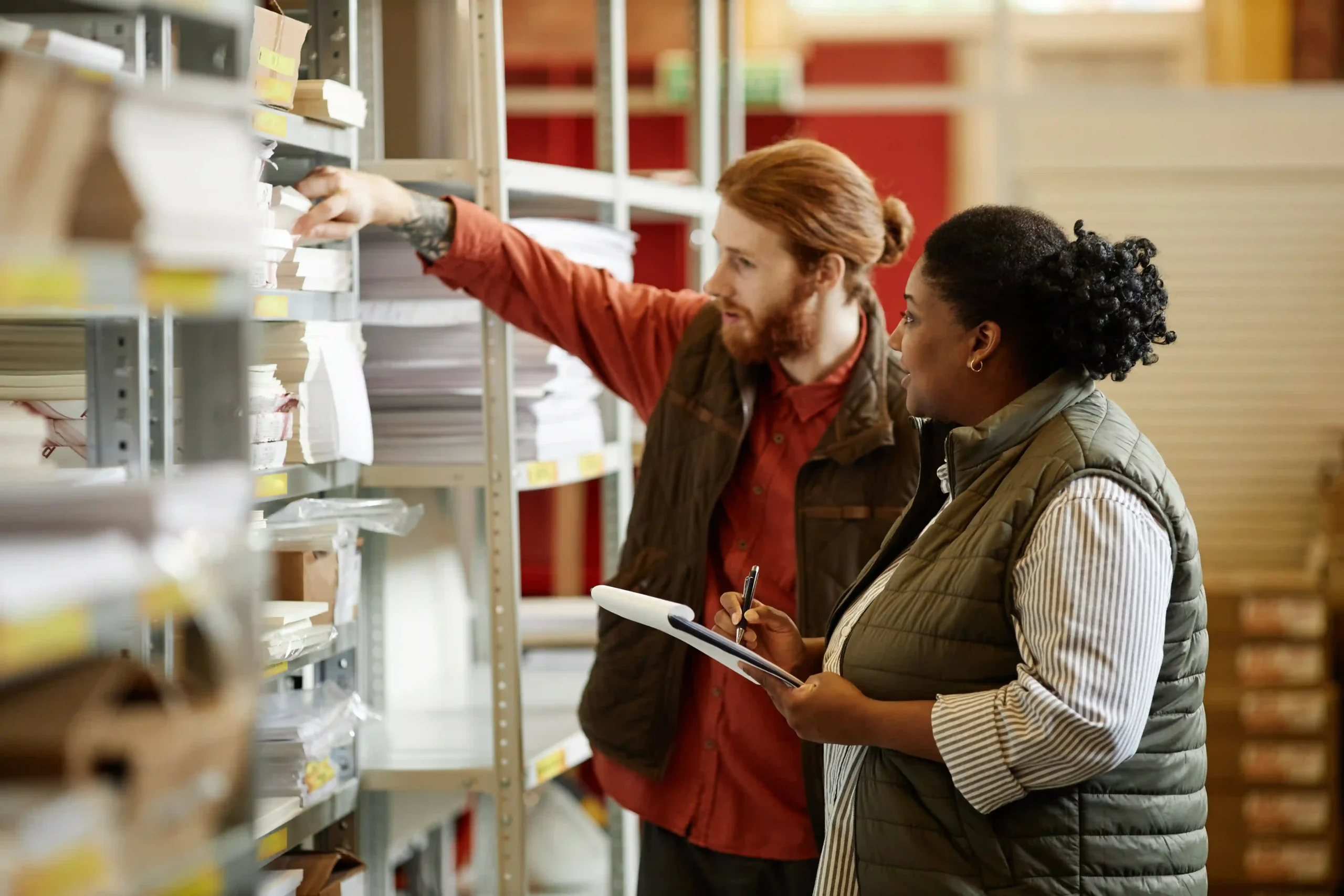 Warehouse employees verifying product inventory using an inventory management system list for stock accuracy.