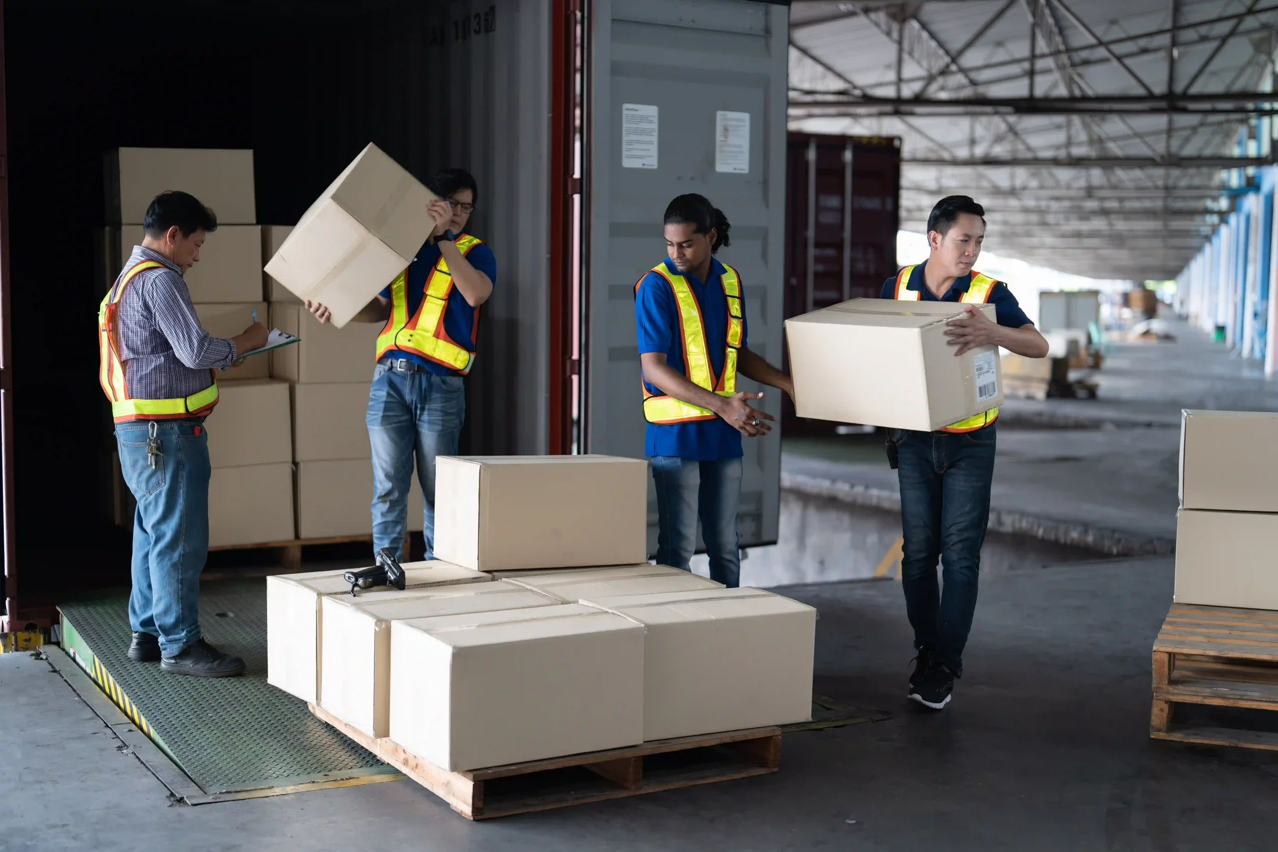 A team of logistics workers unloading a shipping container, highlighting the role of dedicated logistics in freight and supply chain operations.