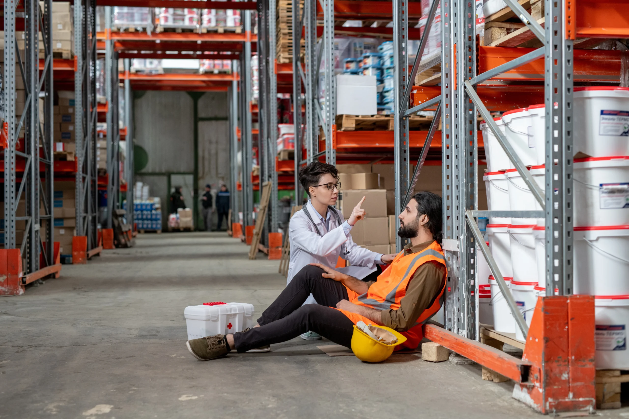 A warehouse employee receiving first aid after an accident, showcasing the safety risks associated with high-speed cross-docking environments.