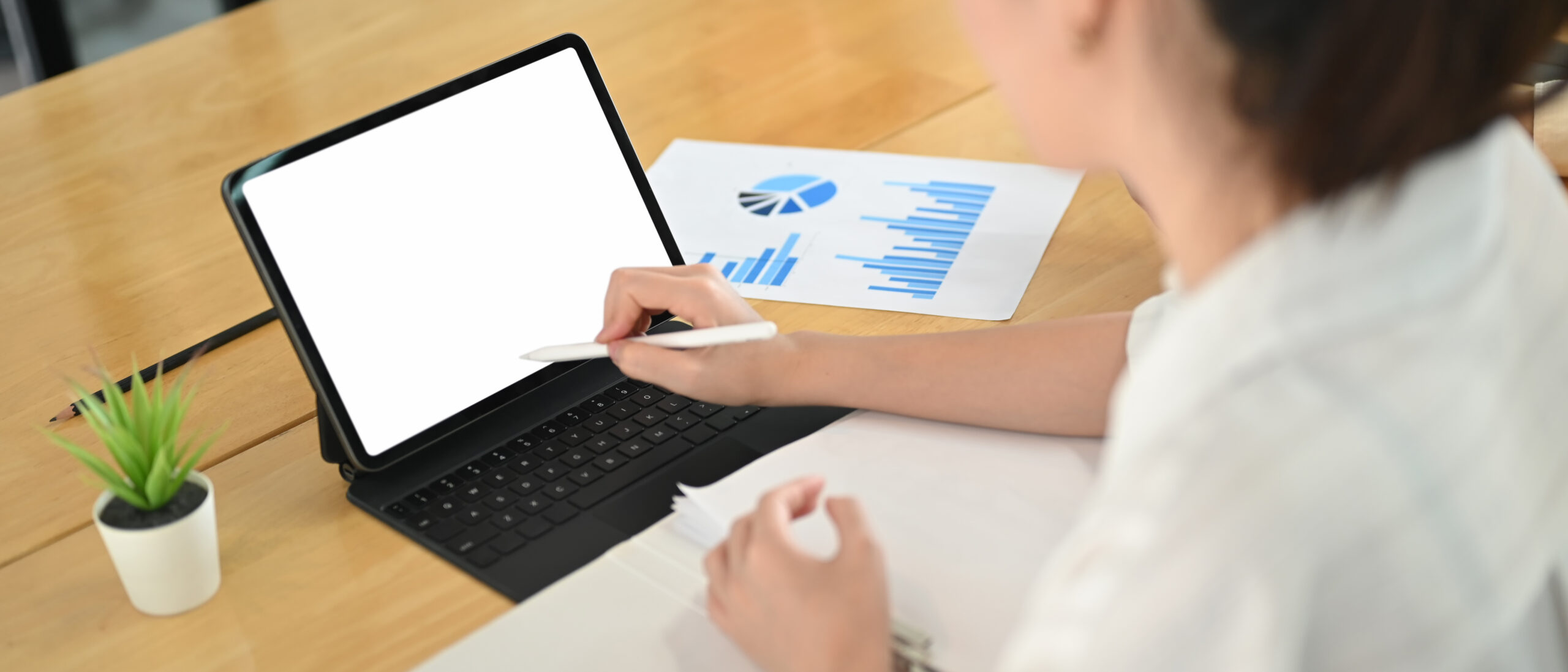 A professional using custom report writing software on a tablet to visualize analytics and generate real-time reports.