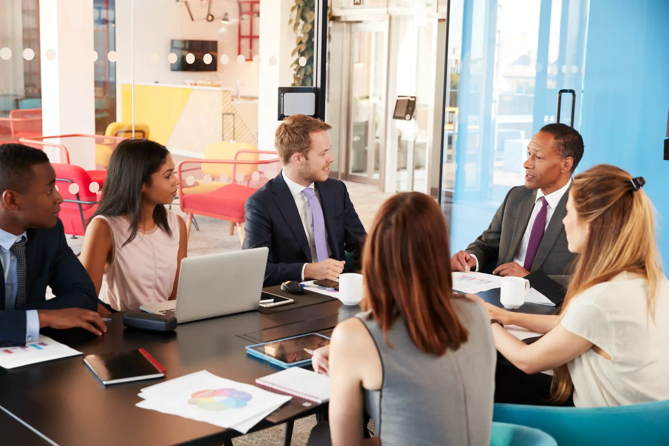 A group of diverse business professionals discussing compliance challenges in a meeting room. Learn what are the most regulated industries and how they impact businesses.