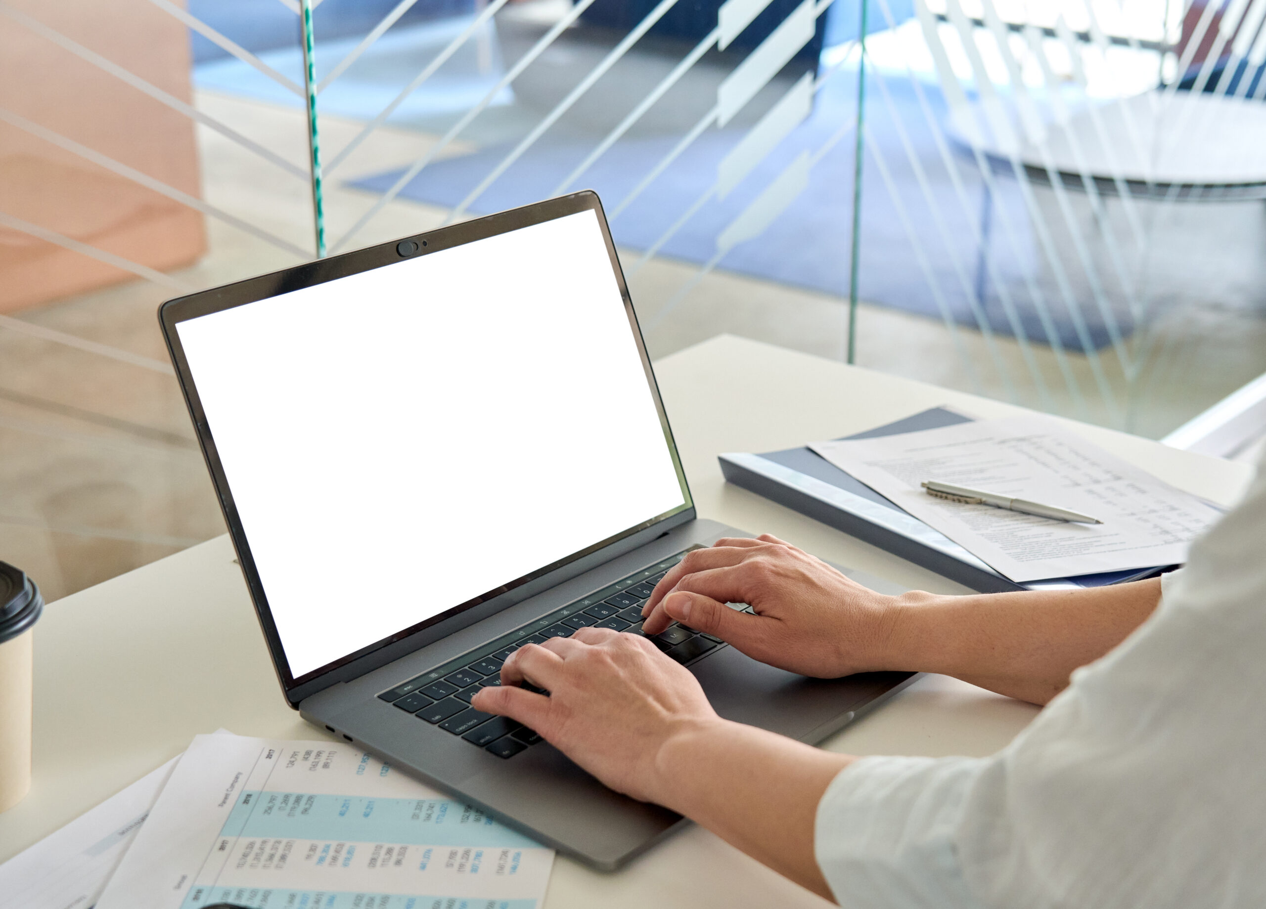 A businesswoman typing on a laptop while generating automated reports with custom report writing software.