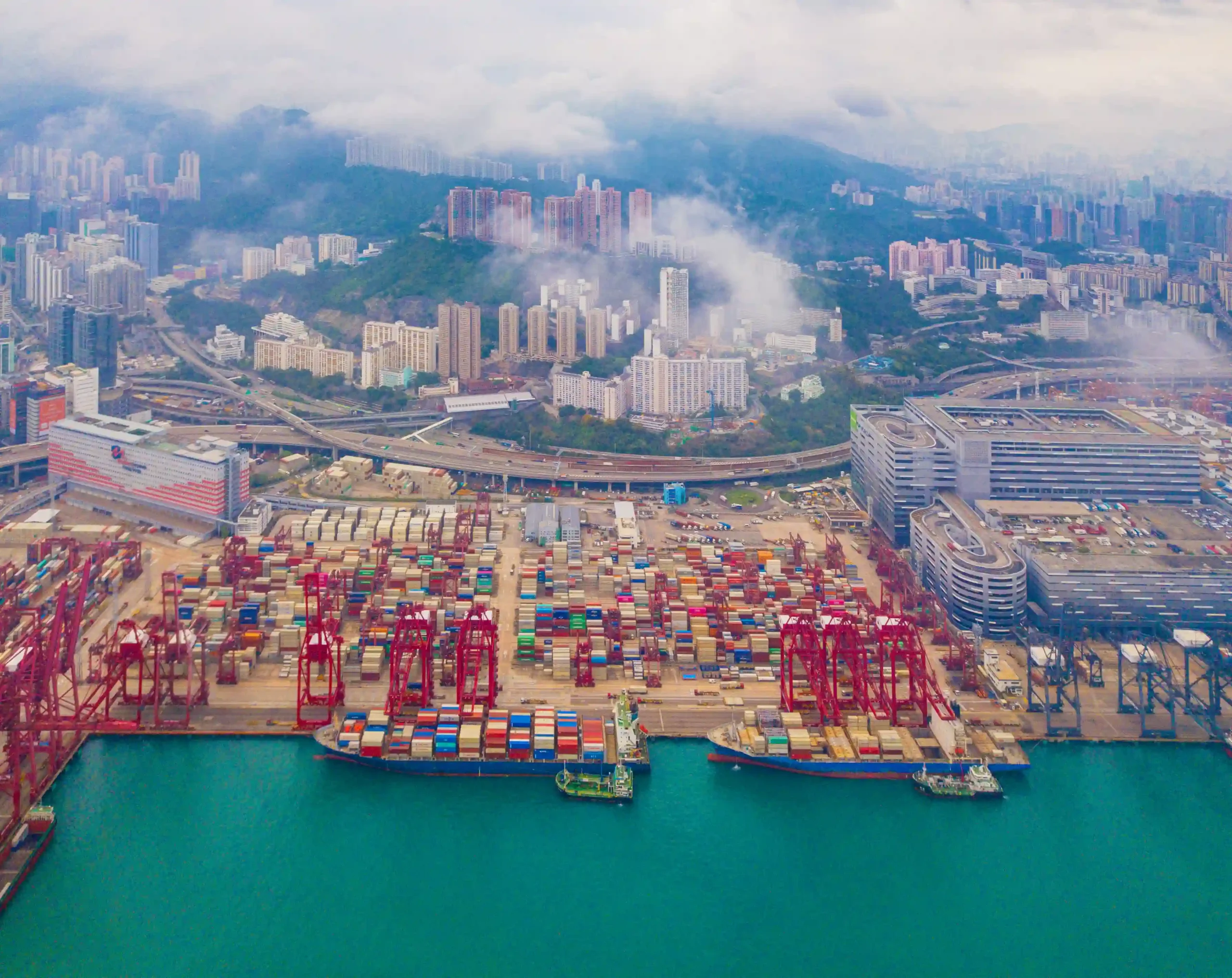 Container terminal with cranes and cargo ships handling imports and exports, showcasing how duty deferral and tariff inversion (FTZ) benefits supply chain management.