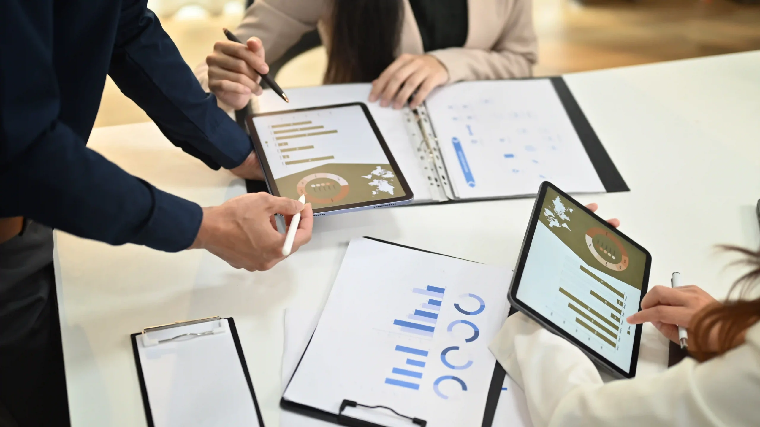 Team collaborating on custom report types using tablets and printed reports, enhancing data visualization and decision-making.