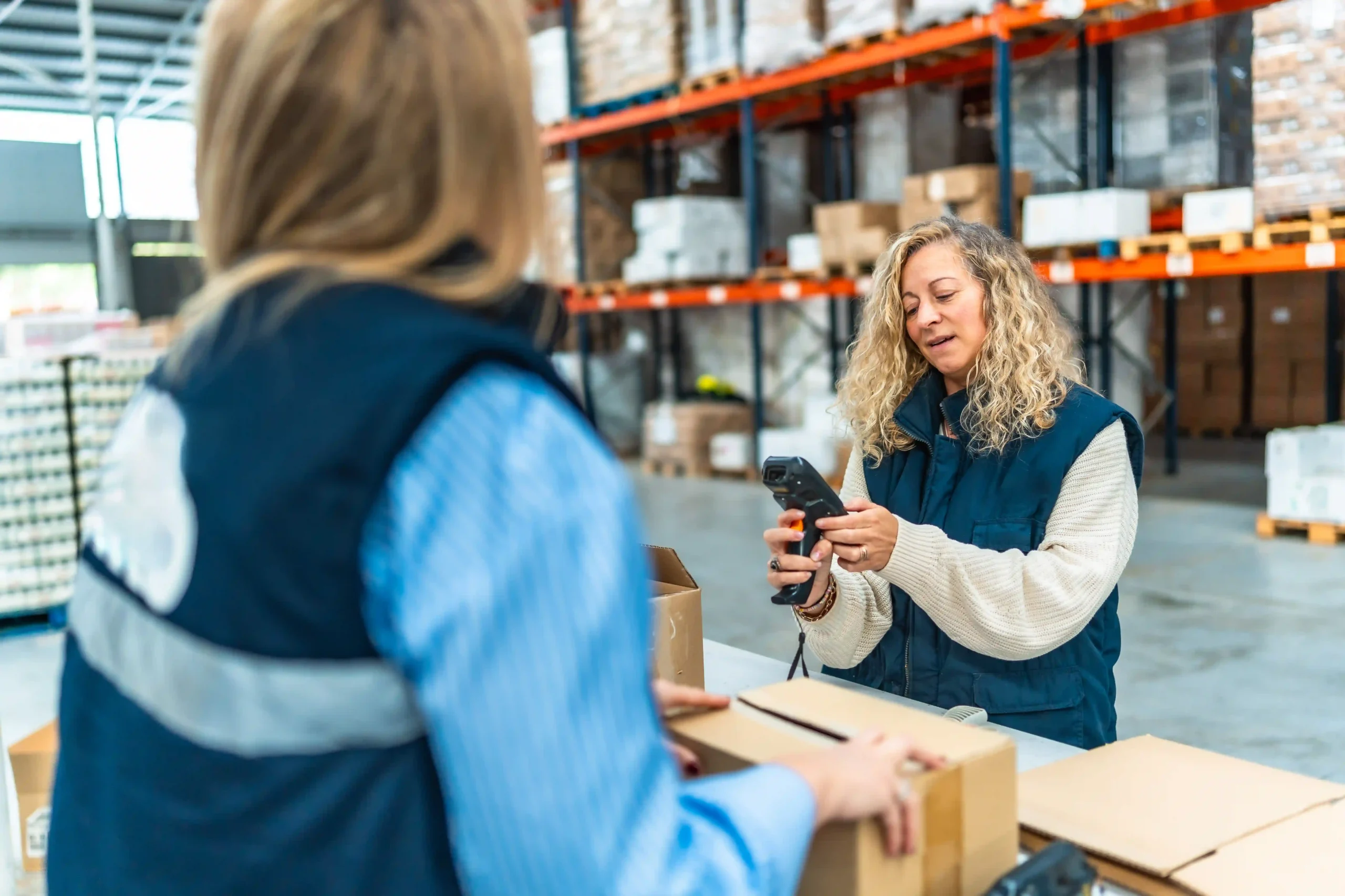 Warehouse employees packing and preparing shipments using real-time supply chain optimization technology for accuracy.
