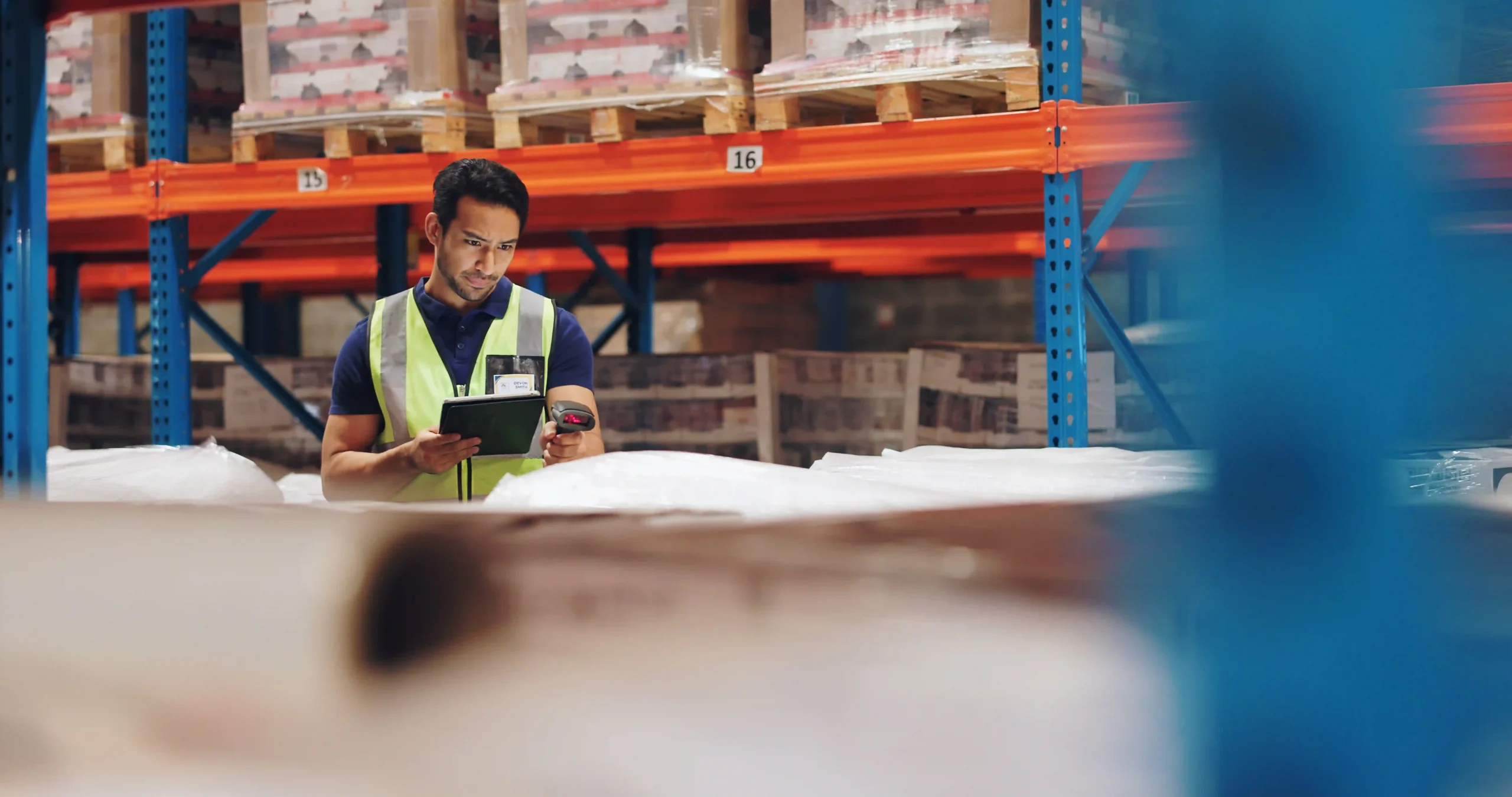 Warehouse worker using a tablet and barcode scanner to enhance supply chain visibility and optimization.