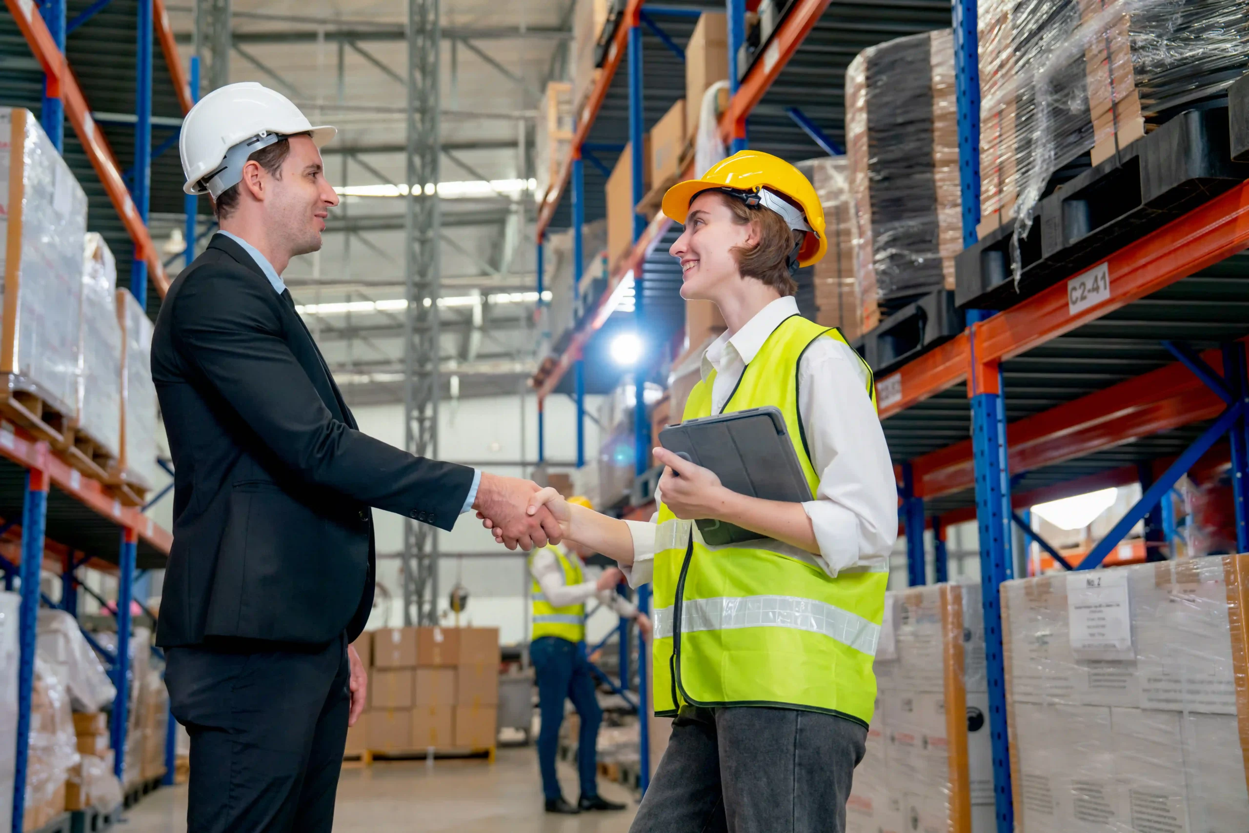 A logistics manager greeting a worker in a supply chain warehouse, representing supply chain innovation definition.