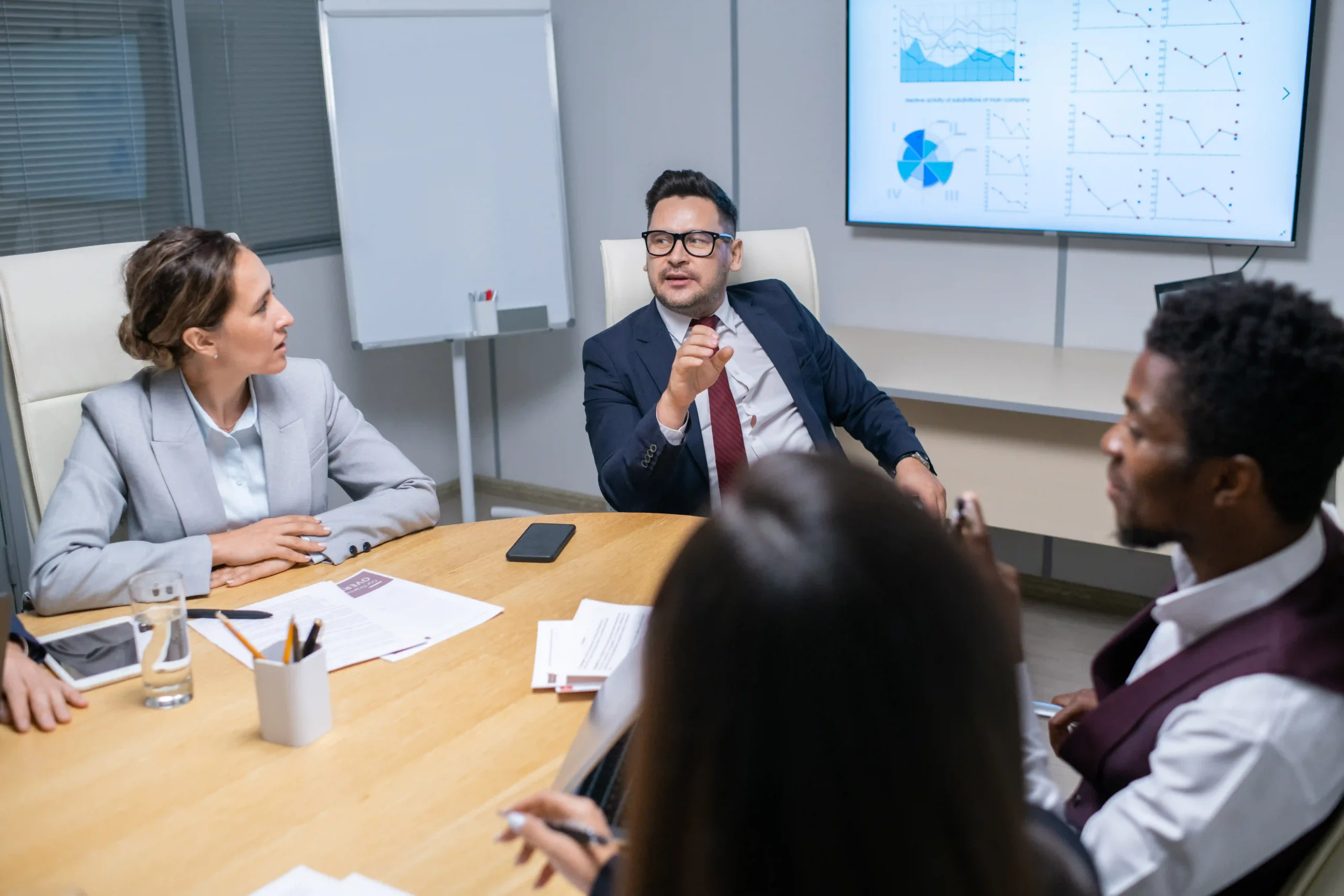 A senior business leader discussing environmental compliance strategies with young managers. The conversation highlights concerns about is EPA reliable in maintaining transparency in environmental policies.