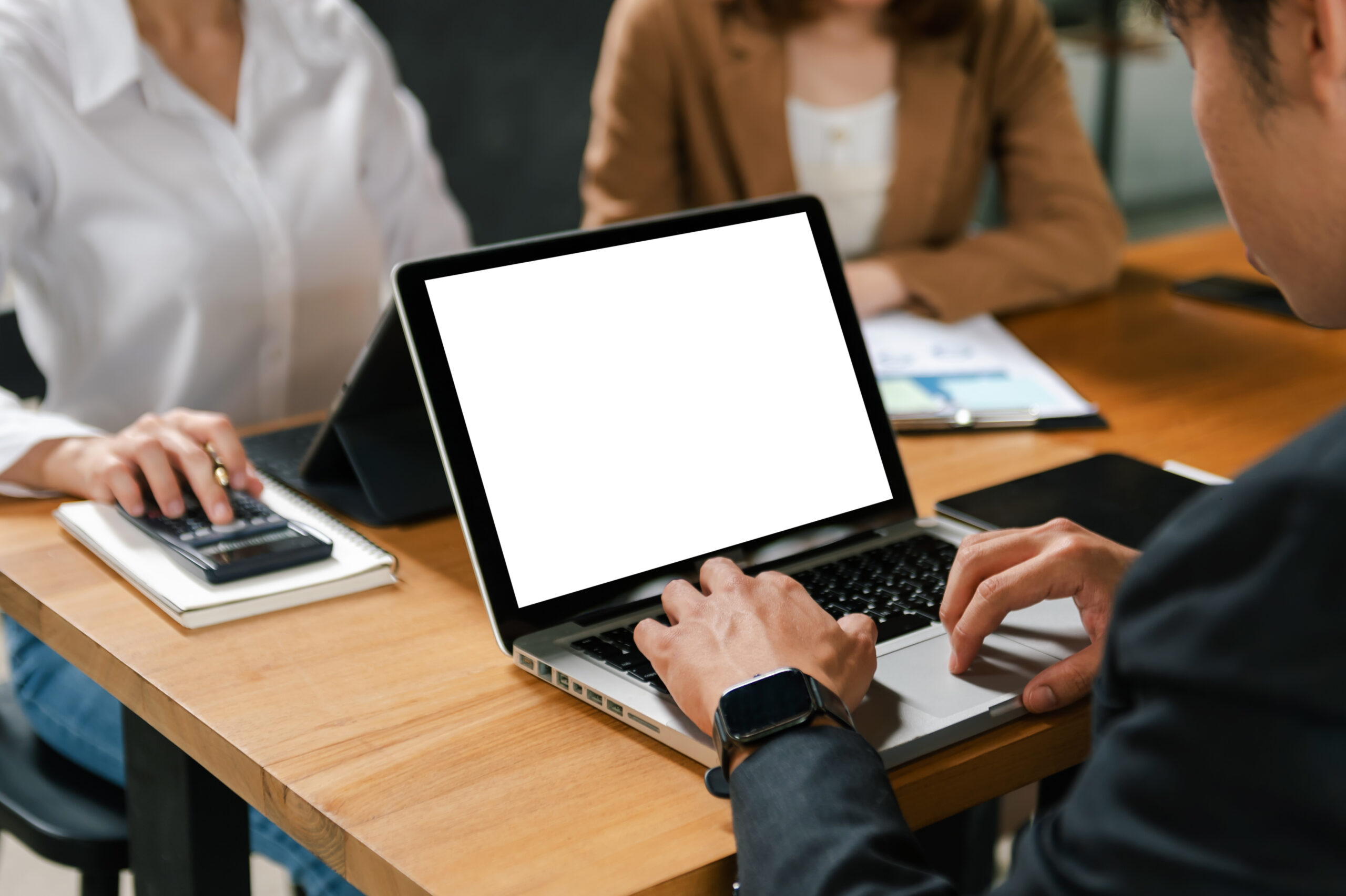 Team collaborating on business insights using custom report writing software displayed on a laptop screen.