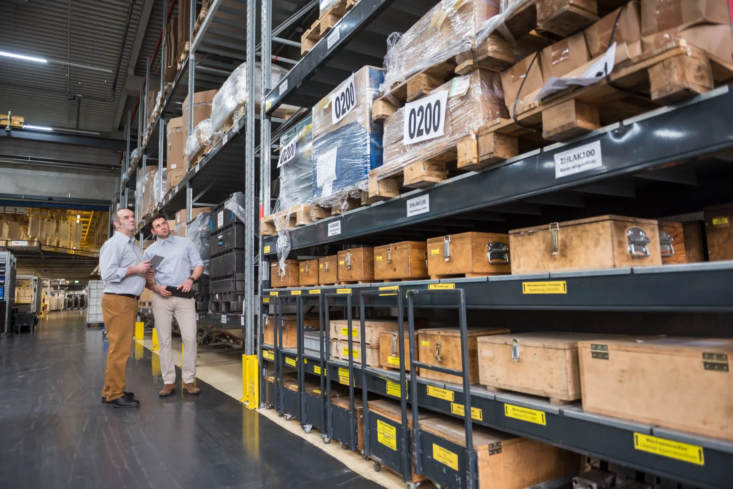 Two logistics professionals evaluating stock levels in an industrial warehouse.