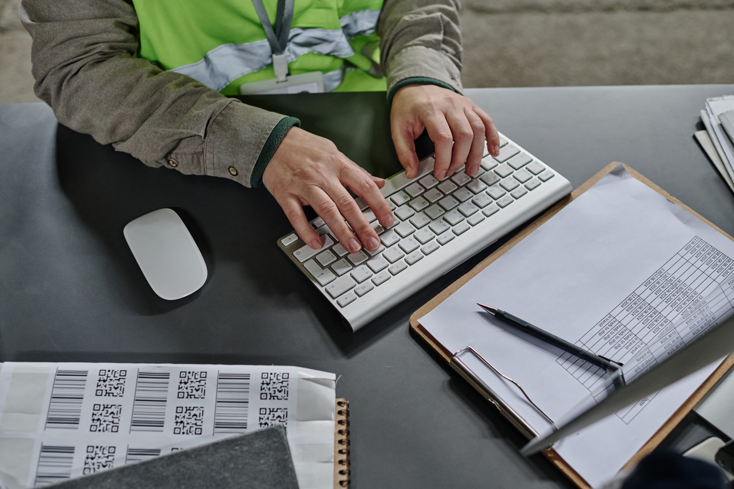 A warehouse worker using custom report writing software on a desktop to track inventory and logistics data in real-time.