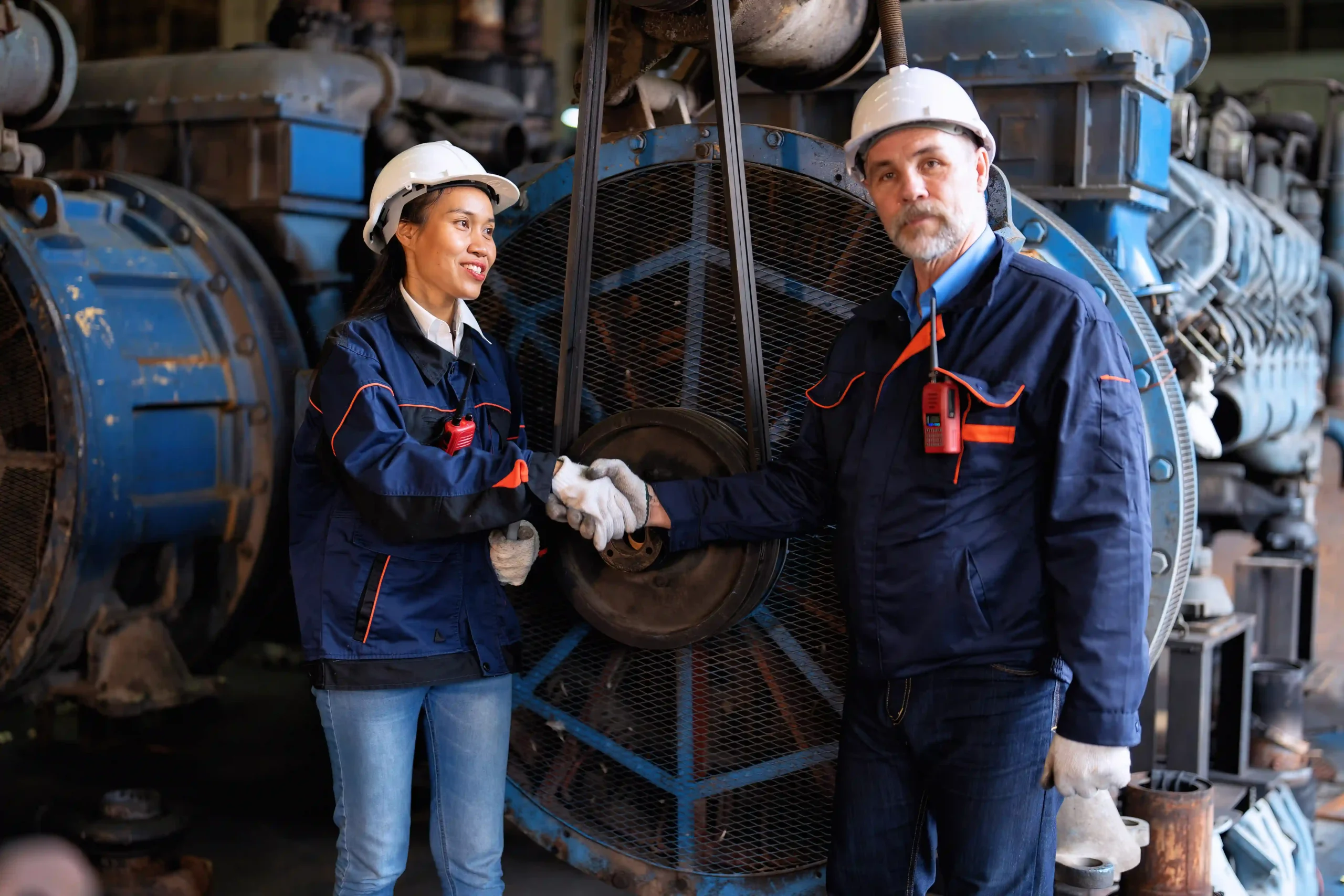 A supervisor and a worker shaking hands in an industrial setting, celebrating compliance achievements in high regulated industries.