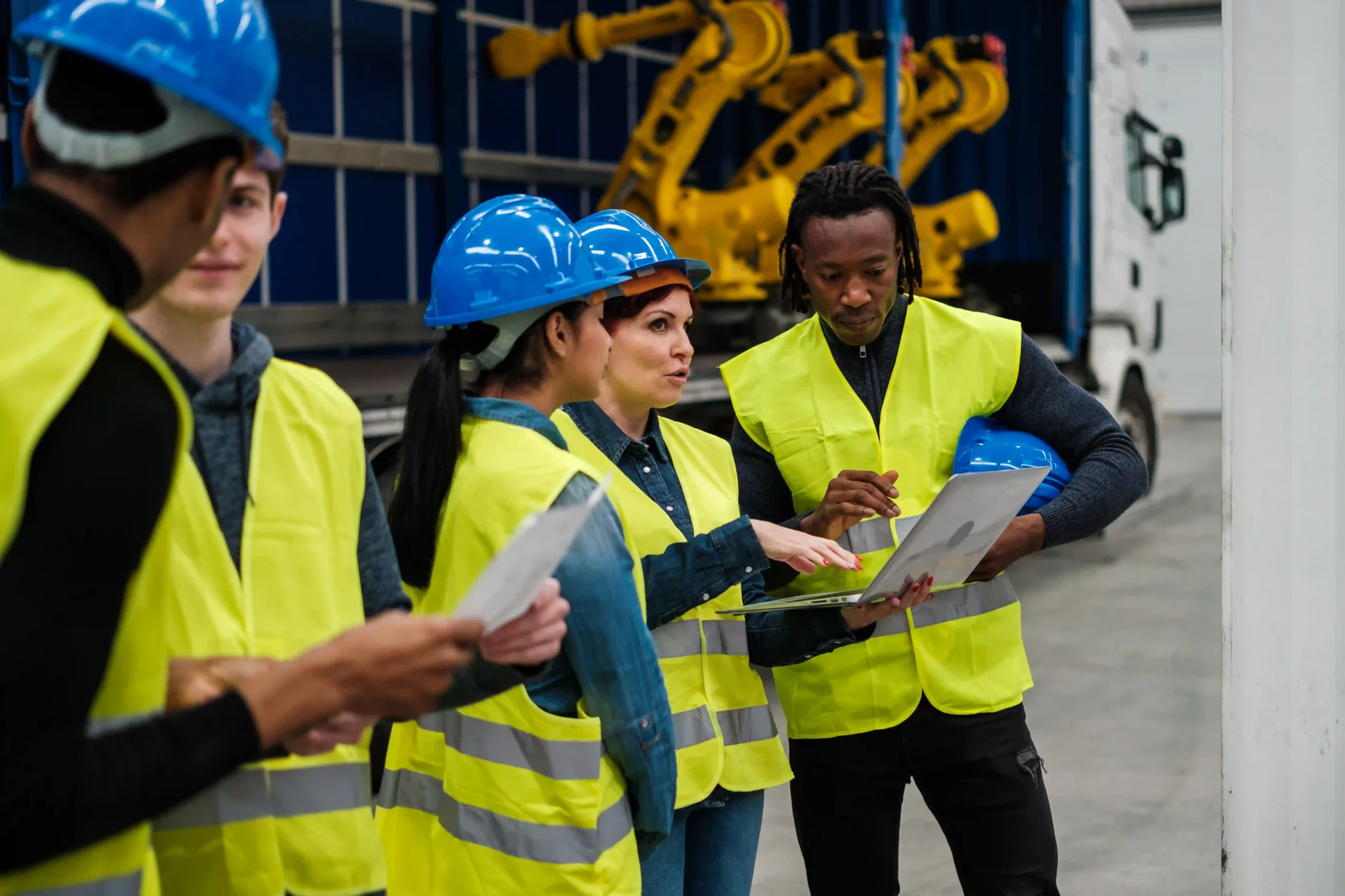 Team of industrial workers using a laptop to track production metrics, emphasizing the value of custom report design.