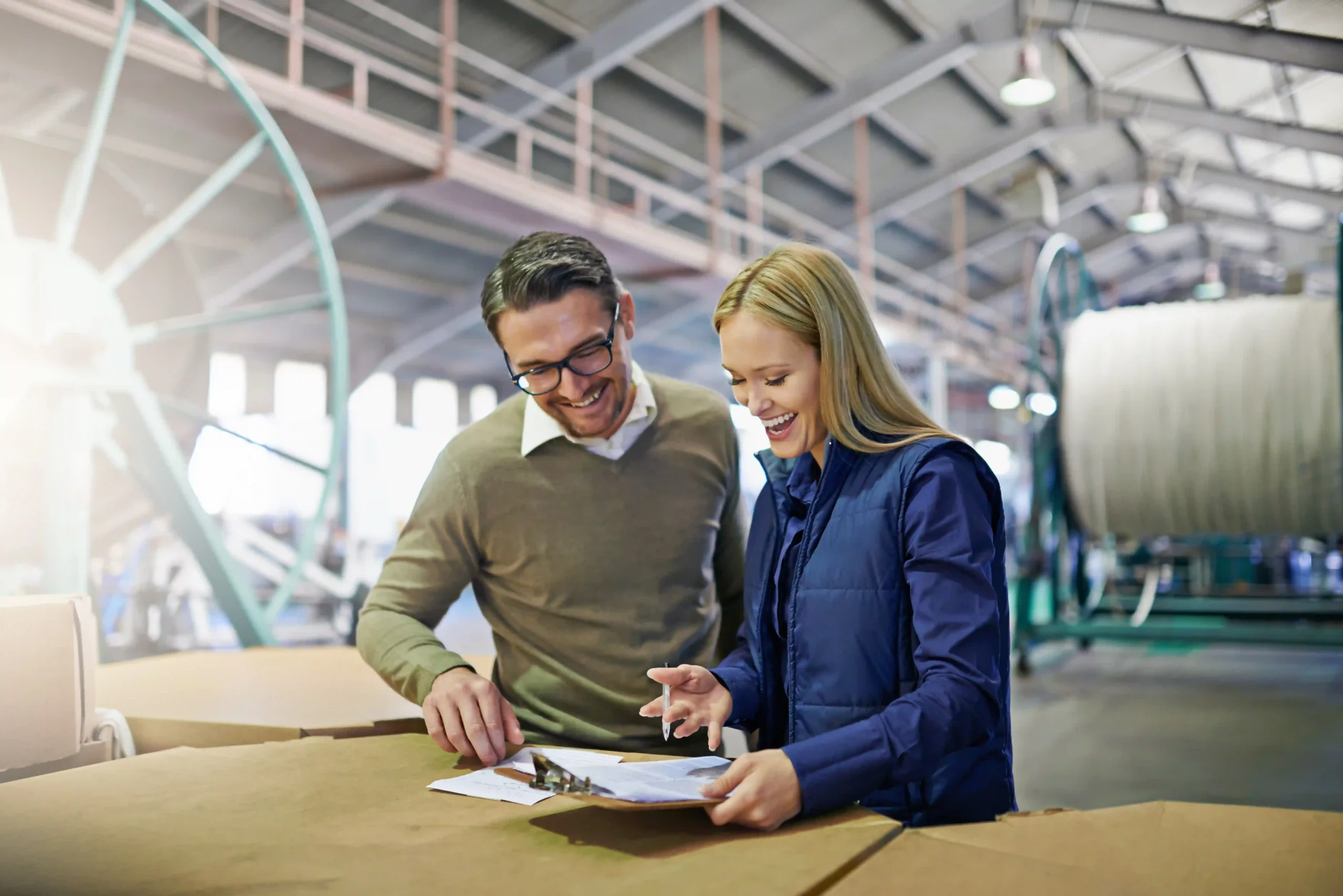 Order fulfillment operator reviewing shipping documents with a colleague inside a logistics facility