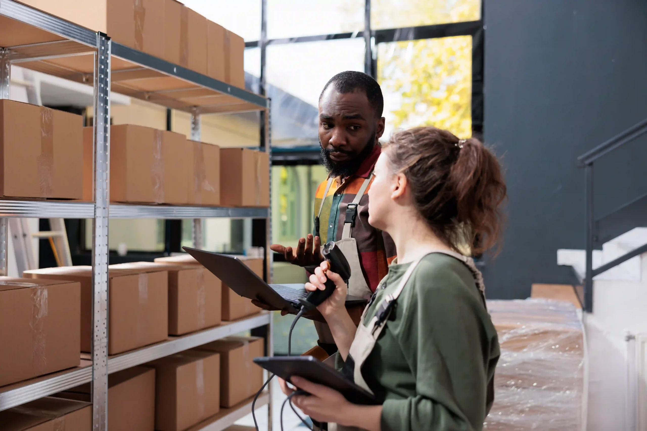 Warehouse staff reviewing inventory management processes with a tablet and scanner at a top 3PL fulfillment company