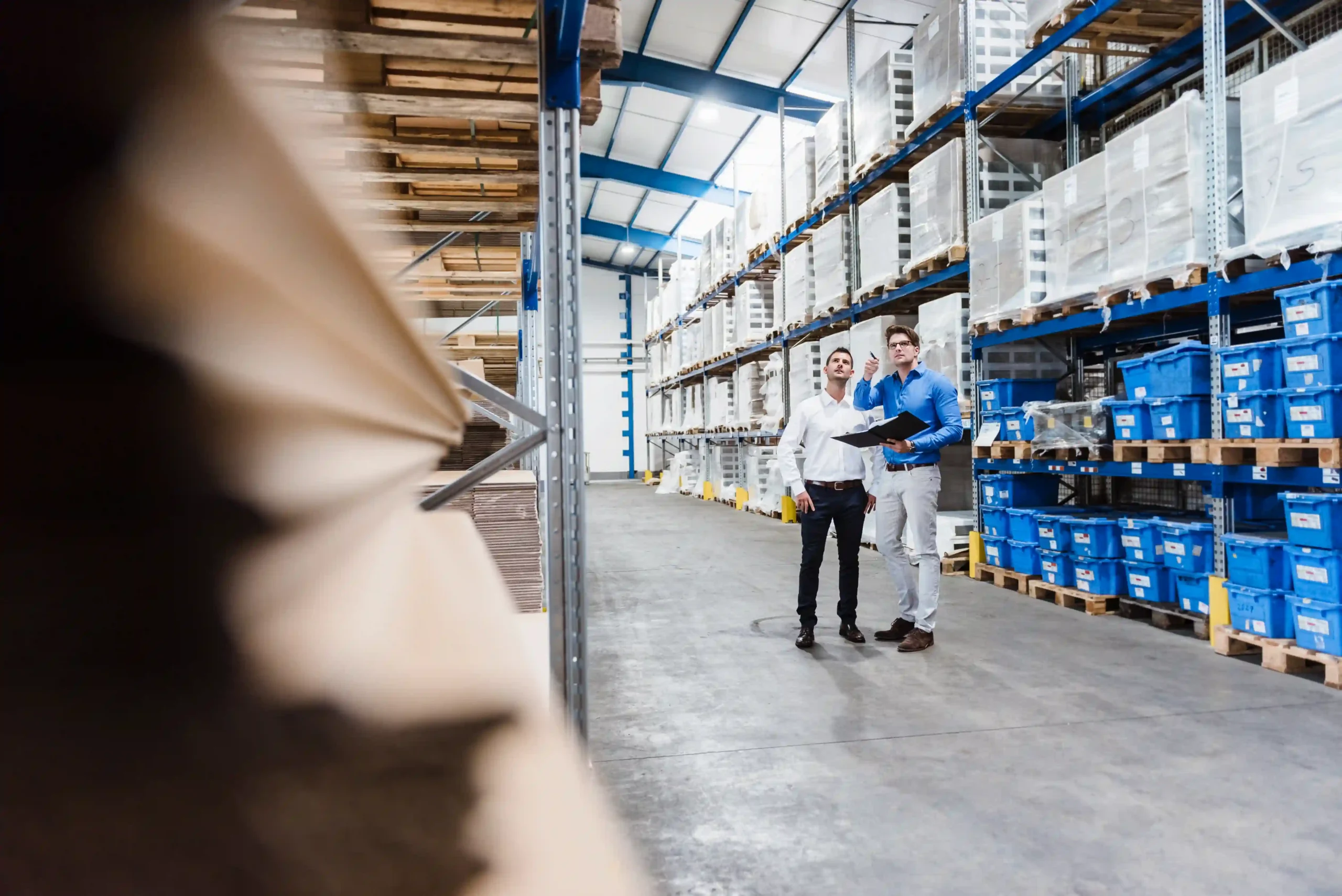 Two managers standing in an FTZ in USA warehouse reviewing logistics and compliance strategies.