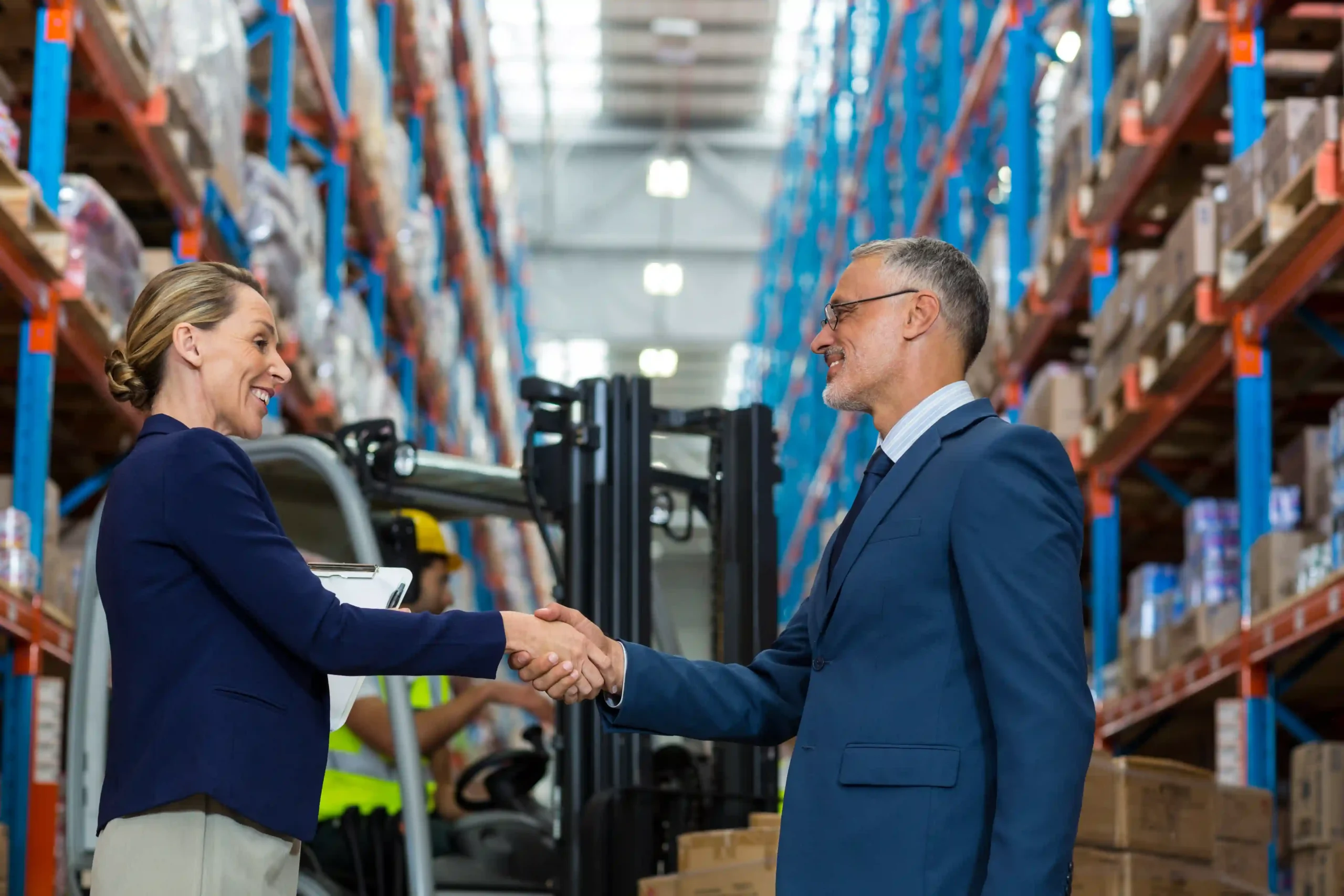 Logistics 3PL company manager shaking hands with client inside organized warehouse