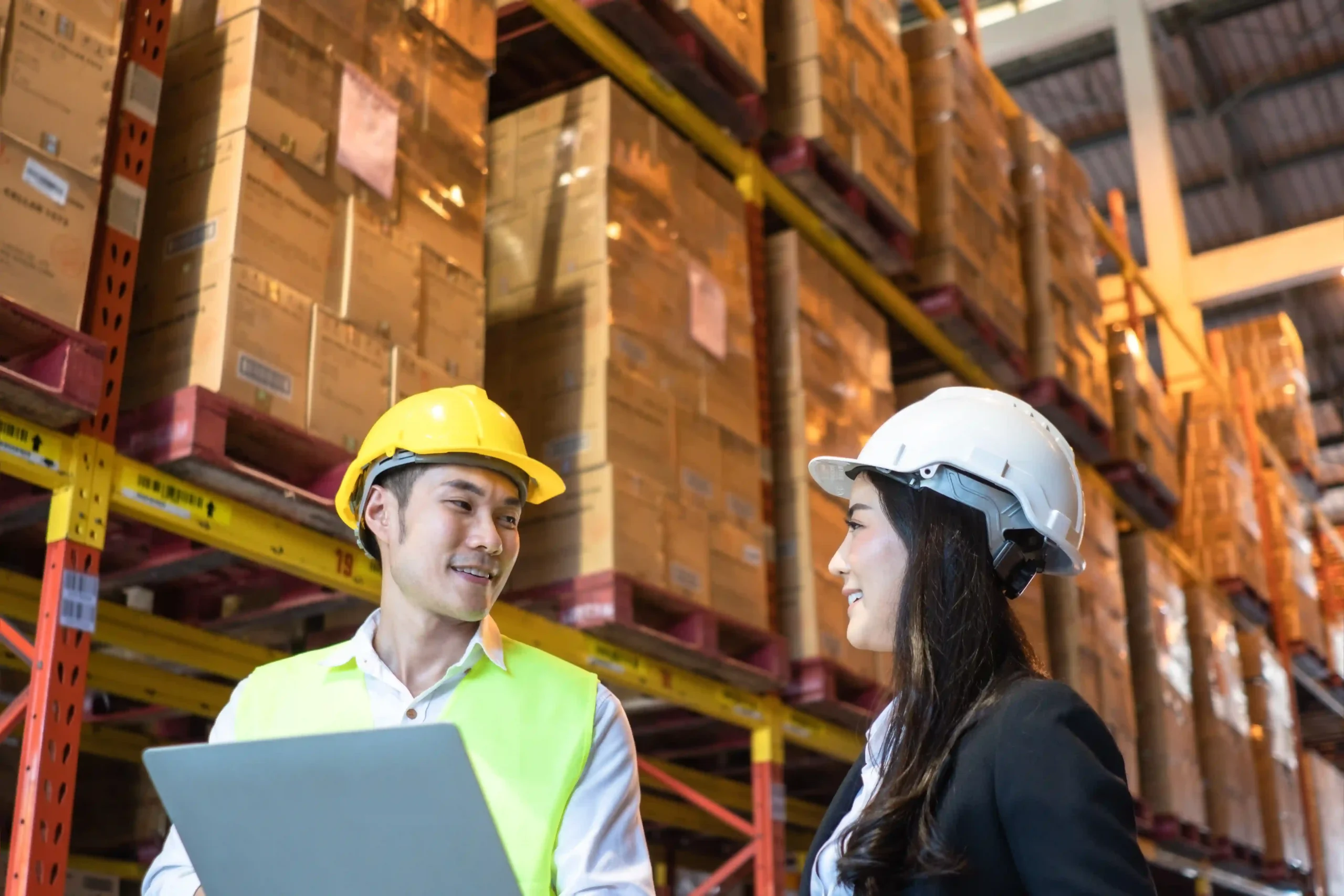 Asian supply chain manager and client discussing supply chain optimization strategies in a warehouse