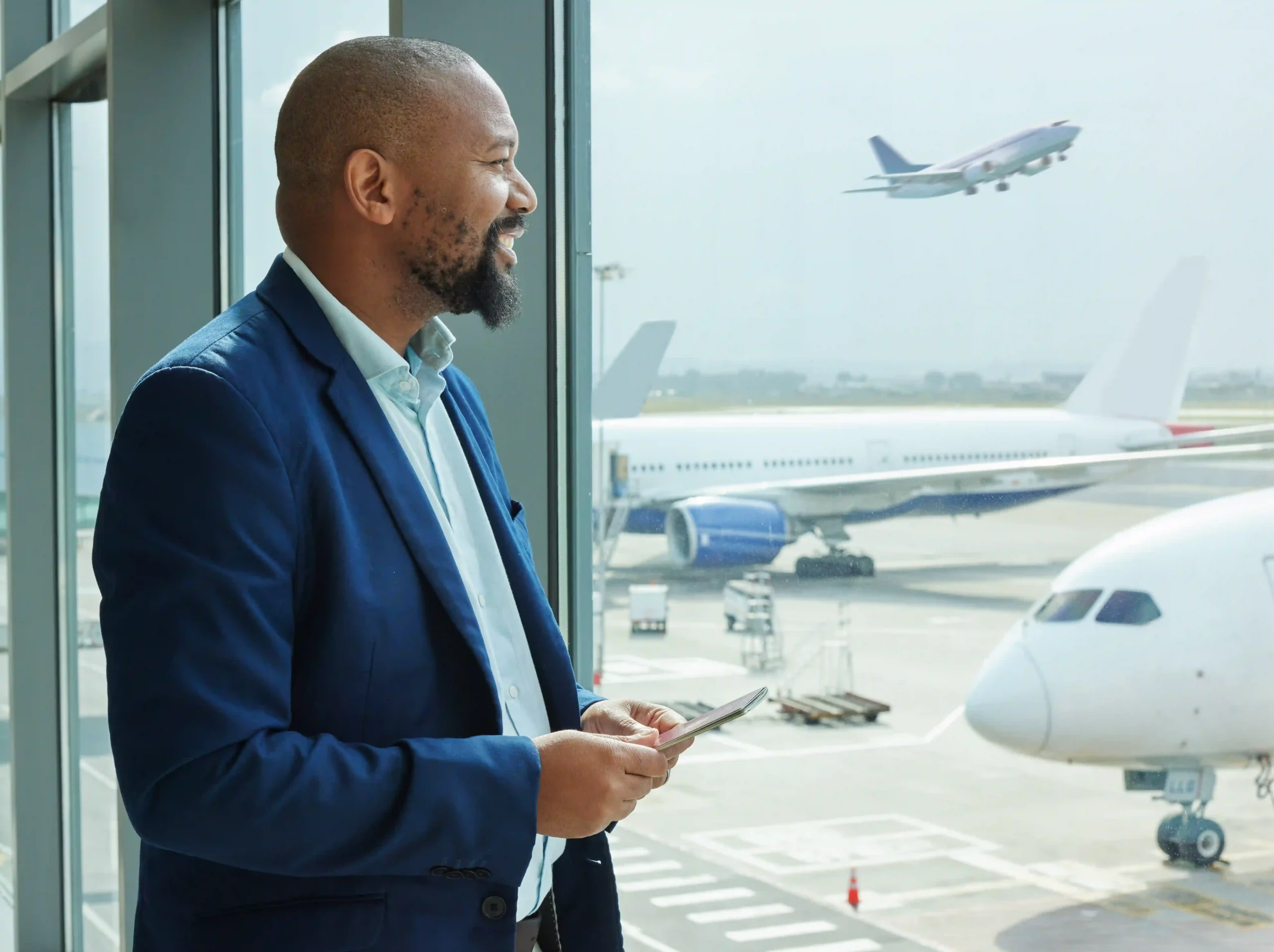 Man in airport terminal looking at airplanes while checking updates for aviation logistics companies