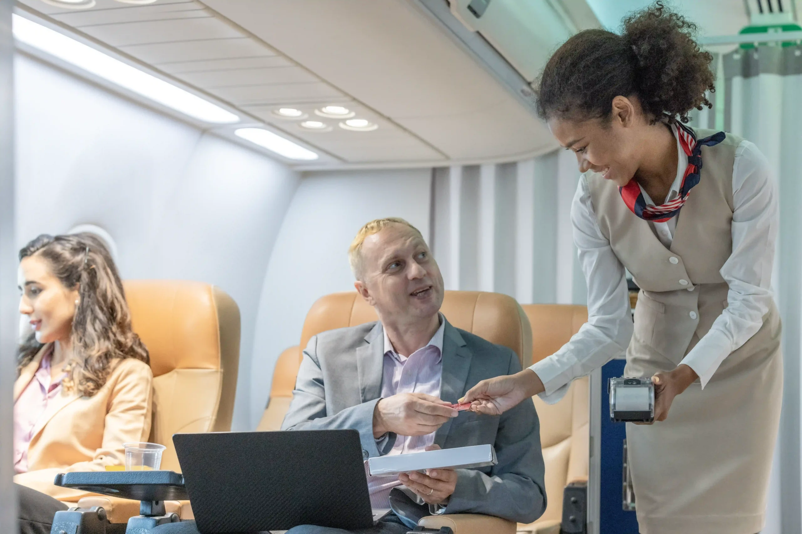 Business traveler paying a flight attendant mid-flight, illustrating customer service in the airline industry description.