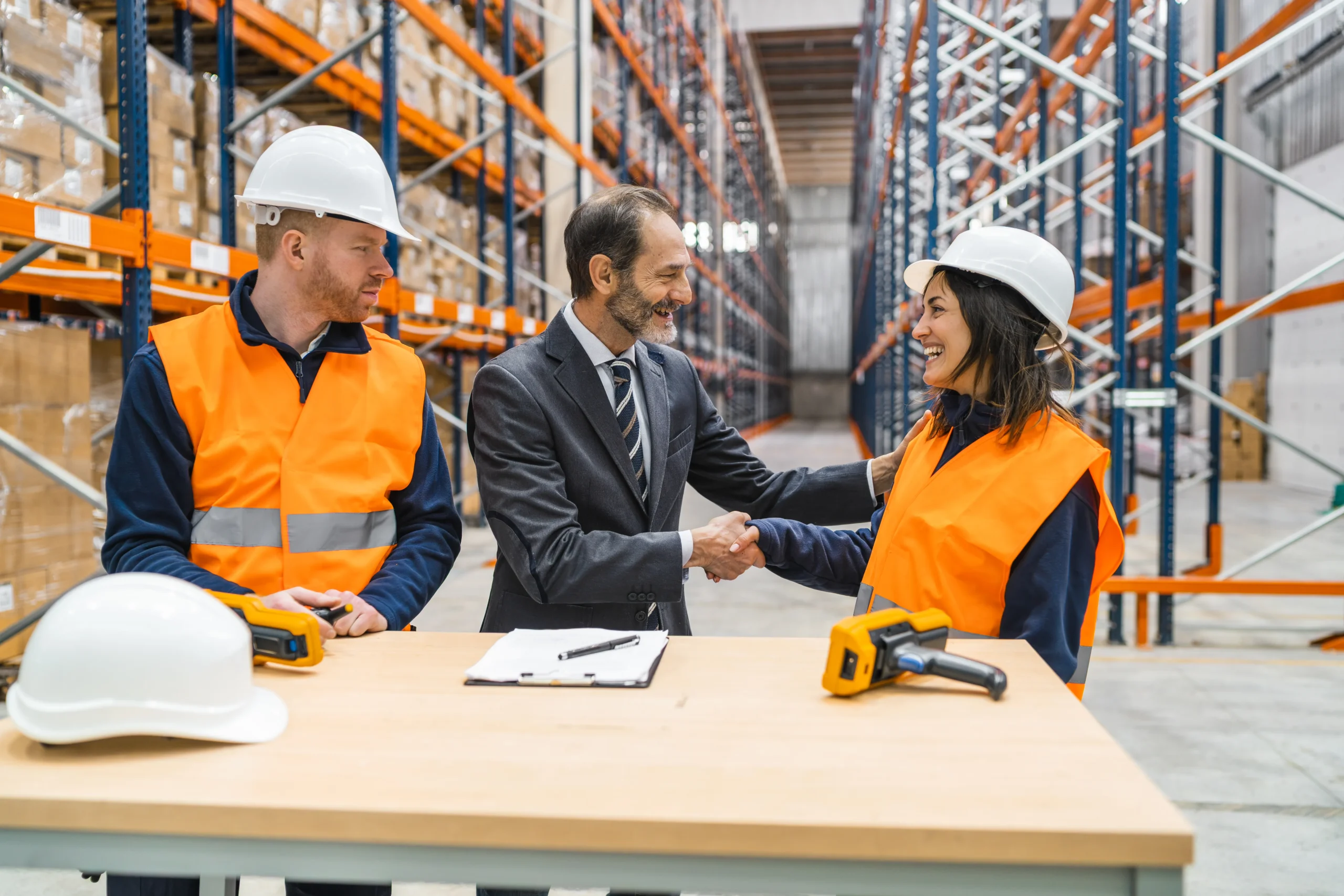 Business leader and warehouse worker shaking hands in a storage facility after a trade compliance management briefing