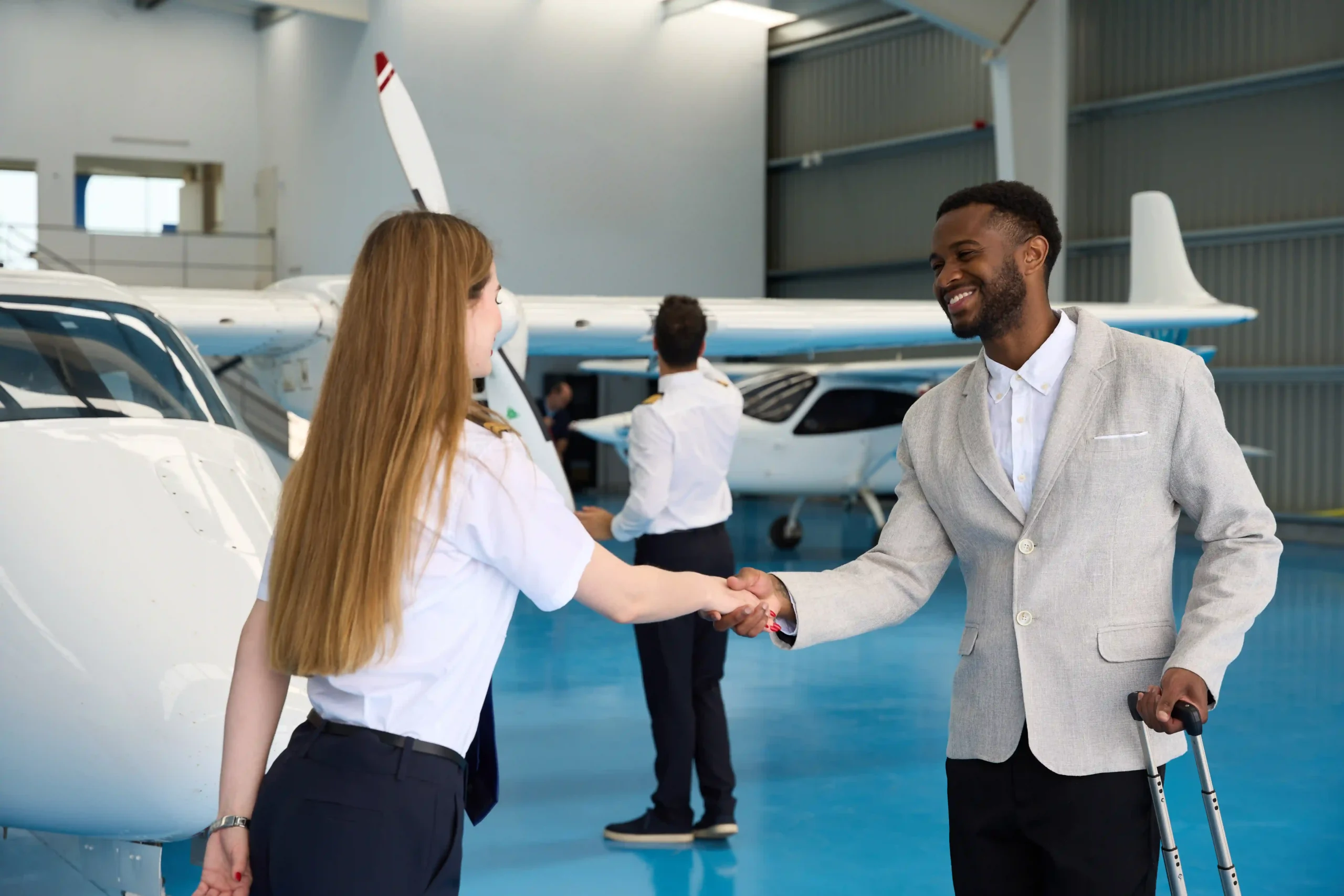 Female pilot greeting a passenger at hangar, highlighting service within the airline industry size.