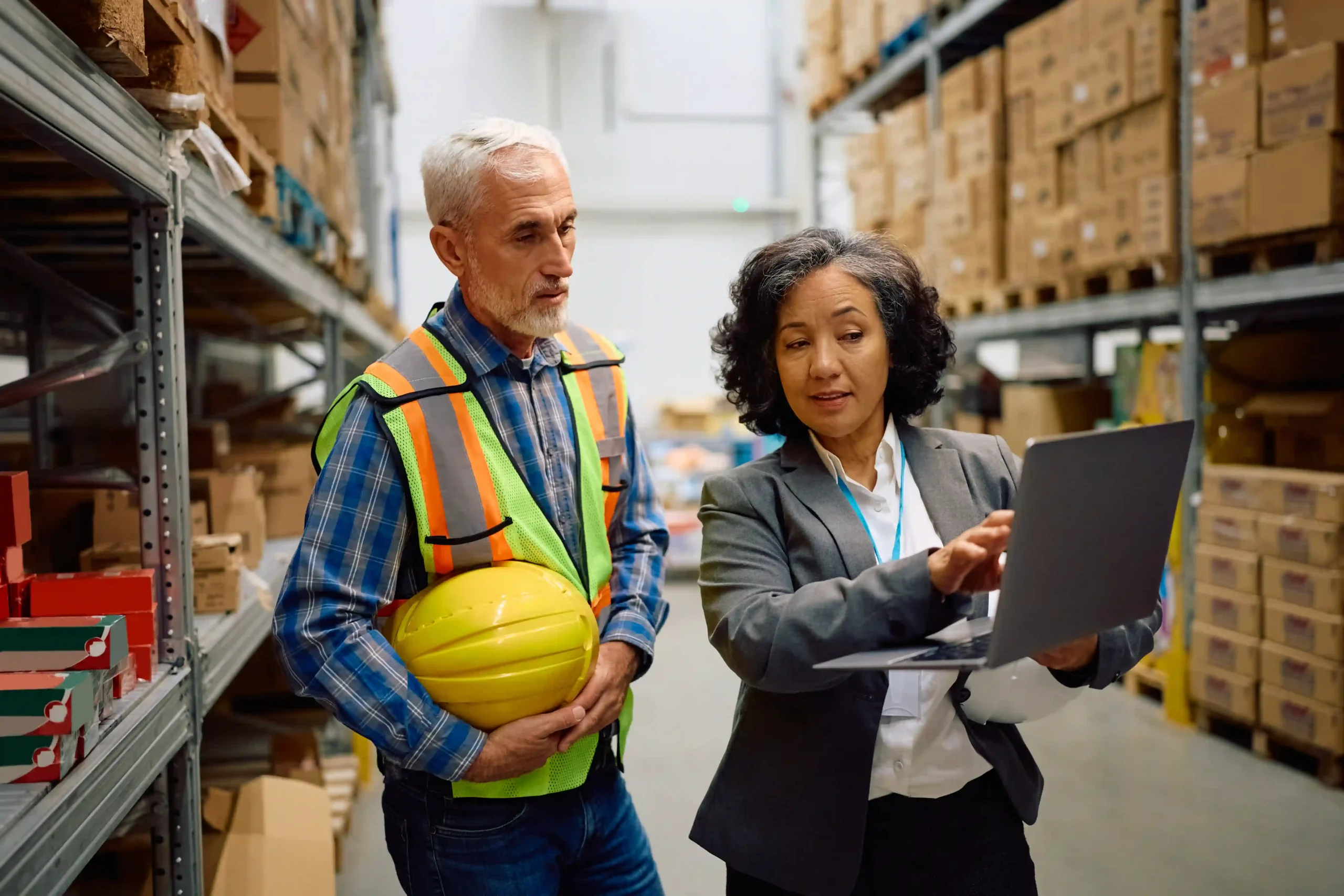 Manager and worker analyzing real-time data on laptop to boost warehouse management experience.