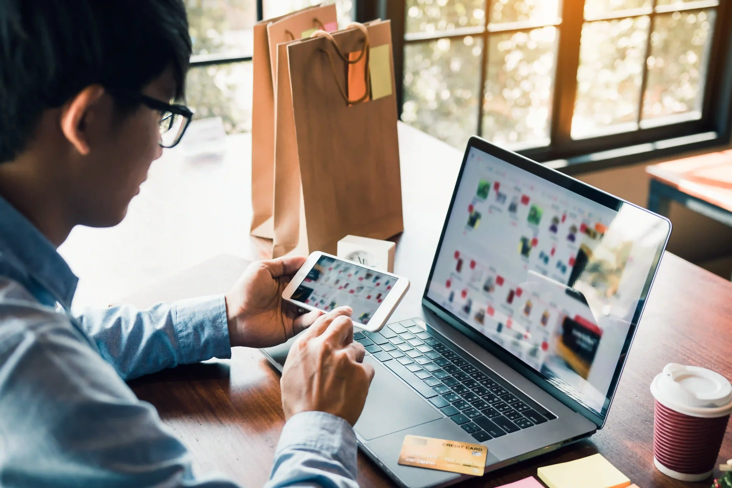 Online shopper using smartphone and laptop, highlighting customer experience in ecommerce fulfillment.