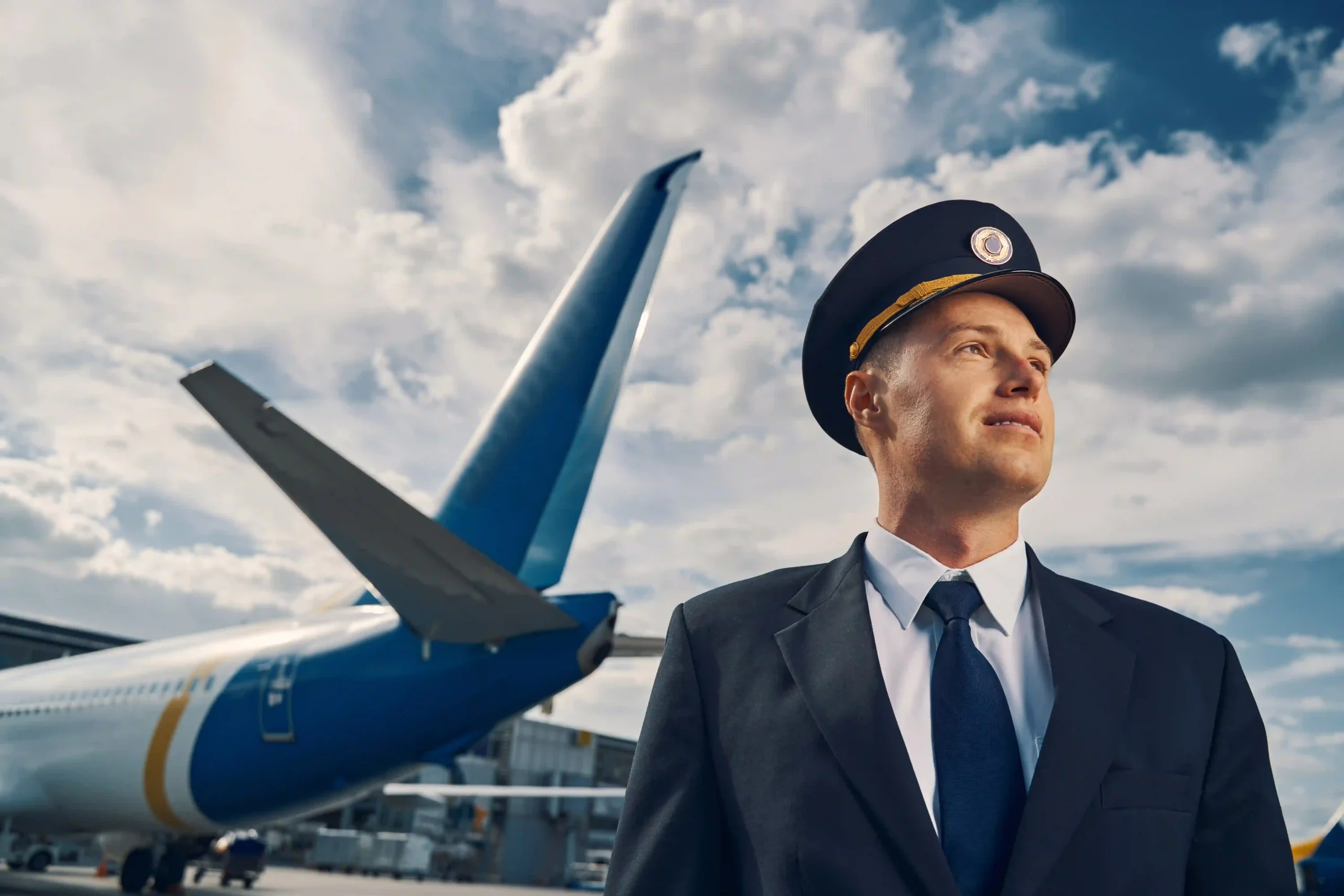 Confident airline pilot standing near aircraft, representing career demand driven by airline industry growth rate.