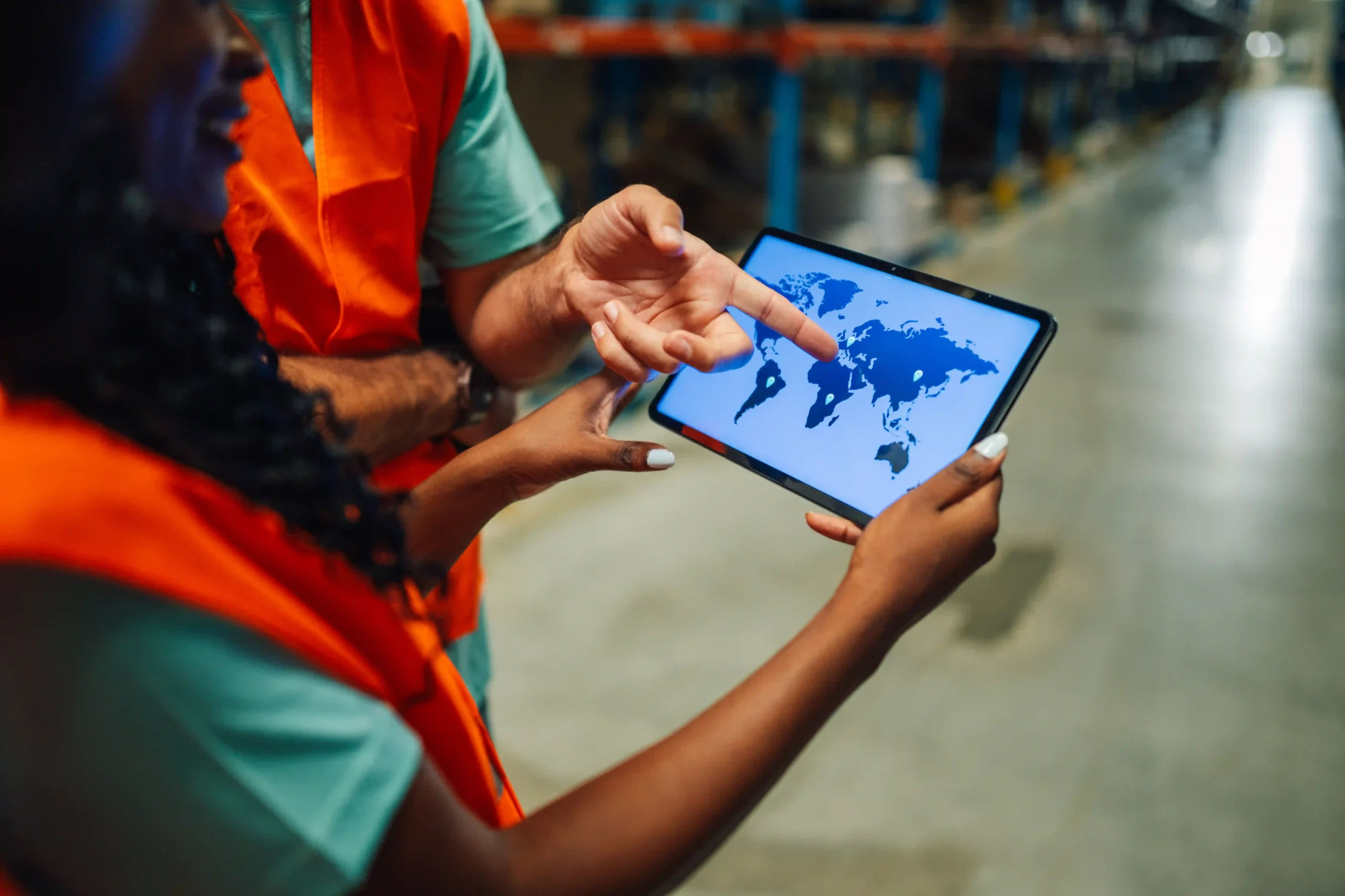 Workers using digital tablet to track global shipments with supply chain optimization technologies Amazon developed.