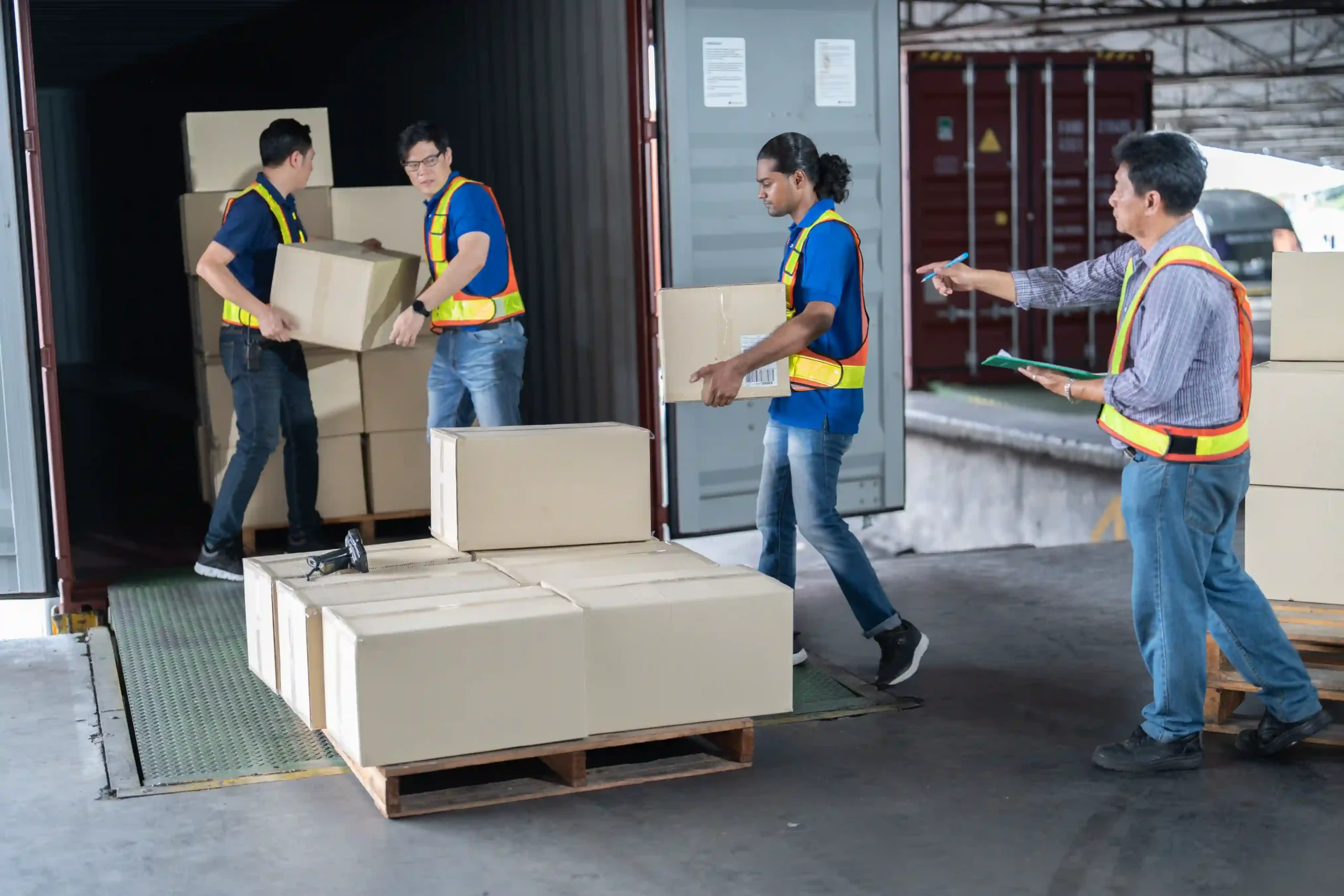 Four warehouse workers managing freight unloading as part of the 3pl logistics process