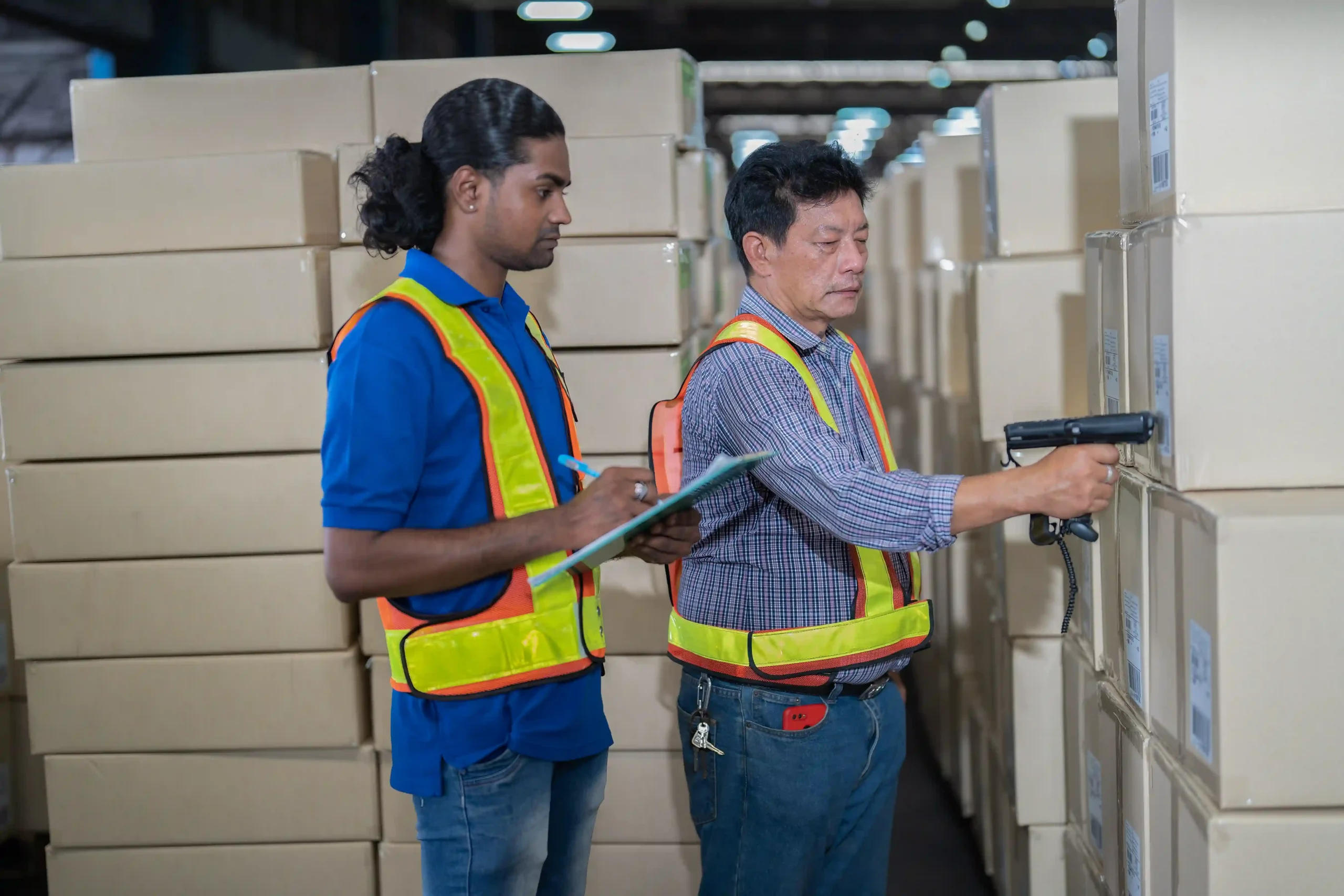 Warehouse staff scanning barcodes on cartons for real-time tracking in inventory management 101 system