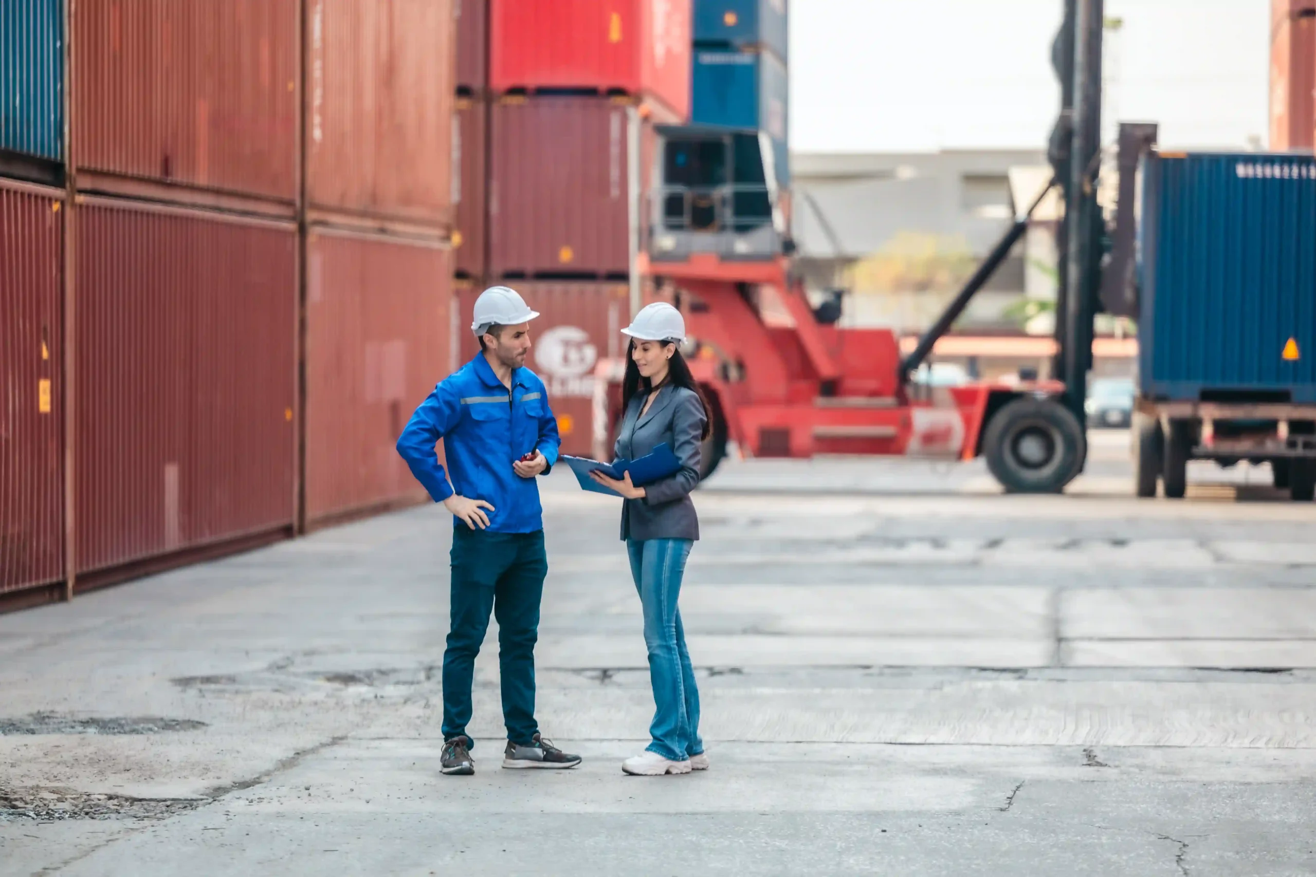 Two logistics workers planning sustainable freight movement in a container yard as part of value added jobs.