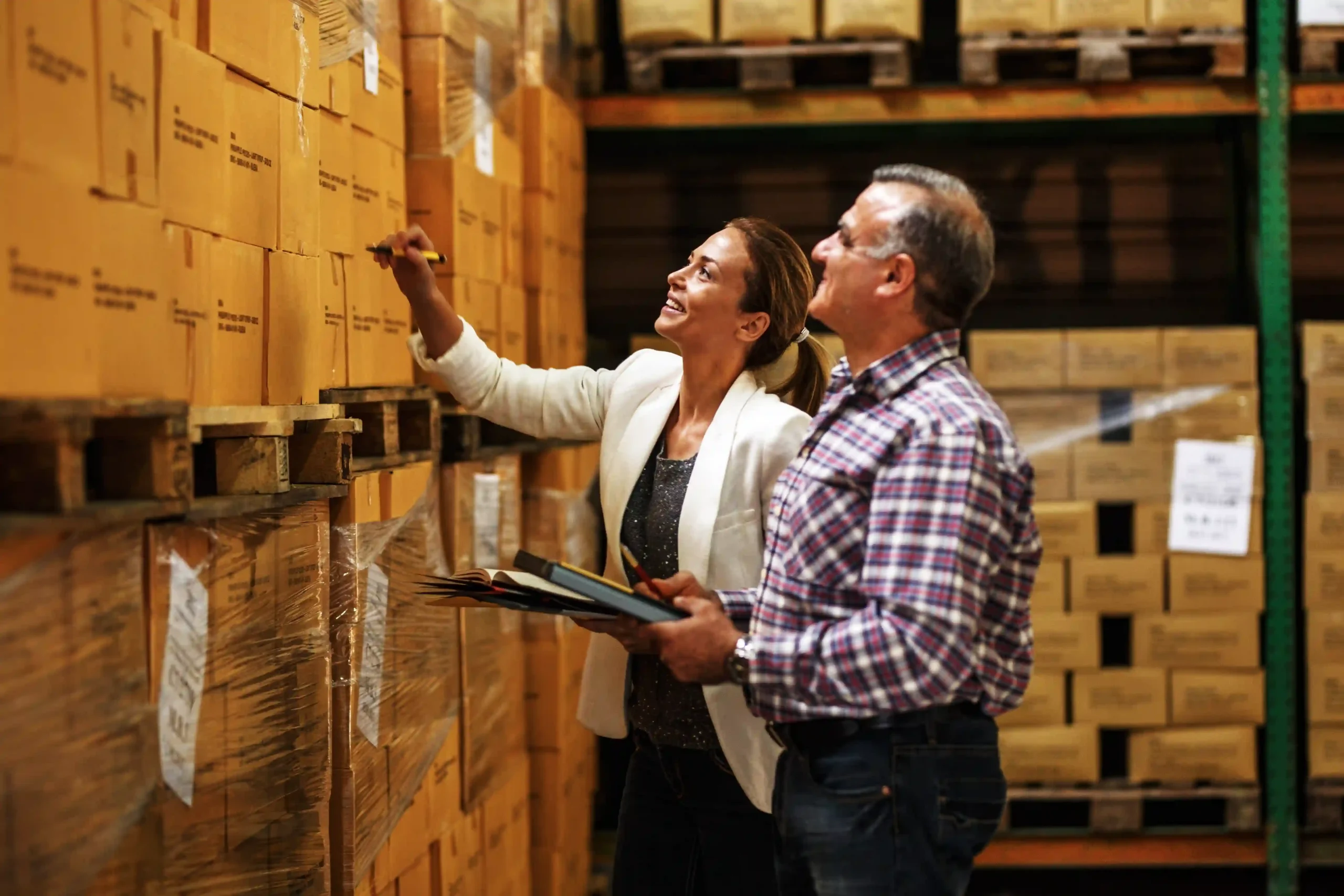 Two team members reviewing box inventory on warehouse shelves as part of inventory management 101 process