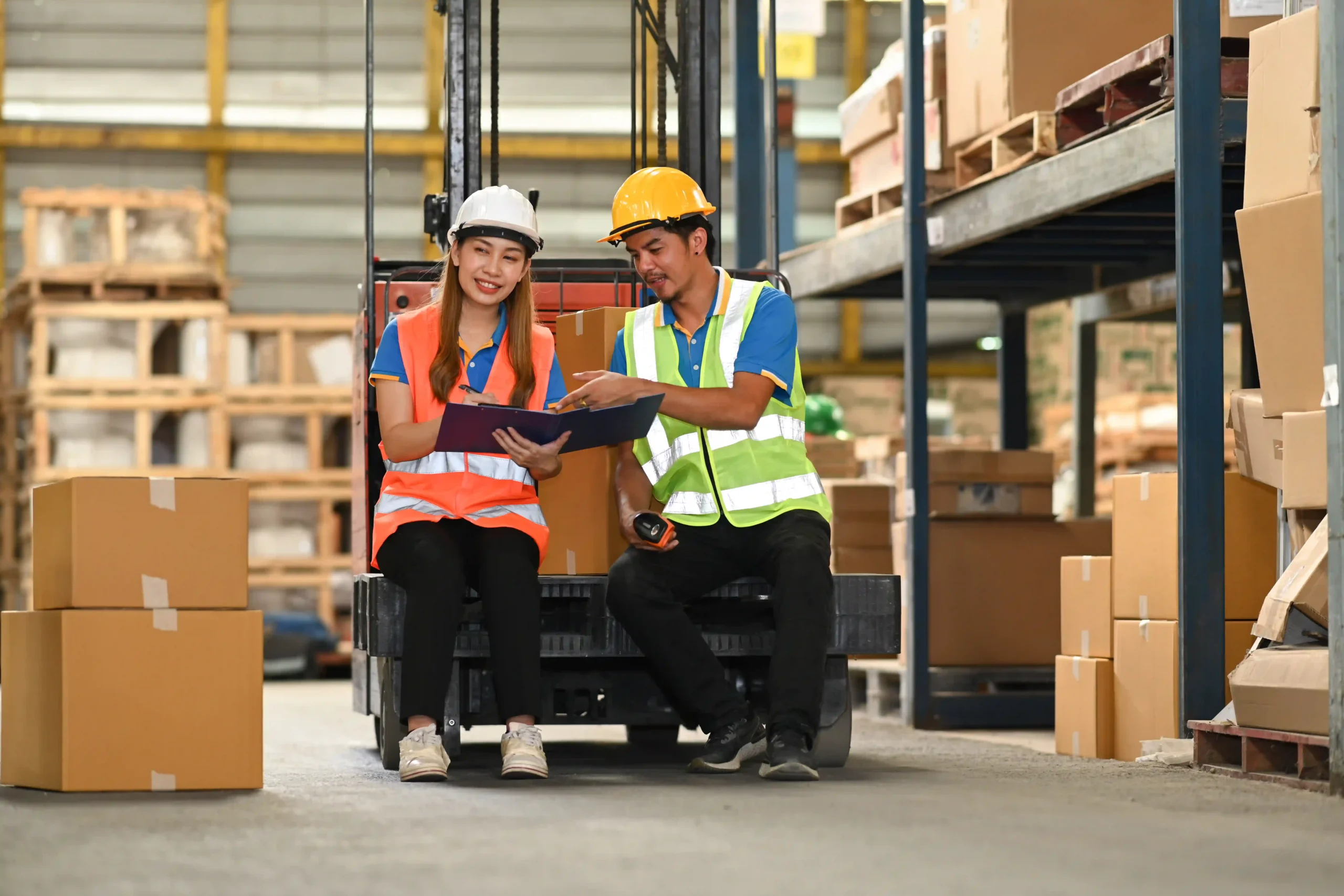 Warehouse workers reviewing a checklist together in a storage facility, utilizing a logistic management information system.